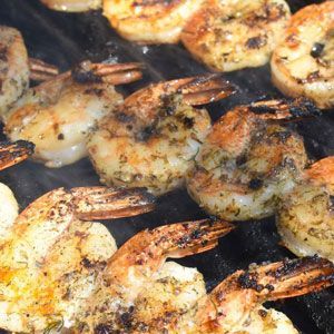 Grilled shrimp on a hot grill, showing browned edges and seasoning.