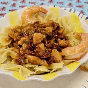 Pasta dish with chicken, shrimp, and sauce; yellow and white plate.