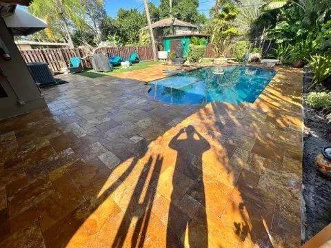 Pool with tan paving, sunny day, shadow of a person taking a photo.