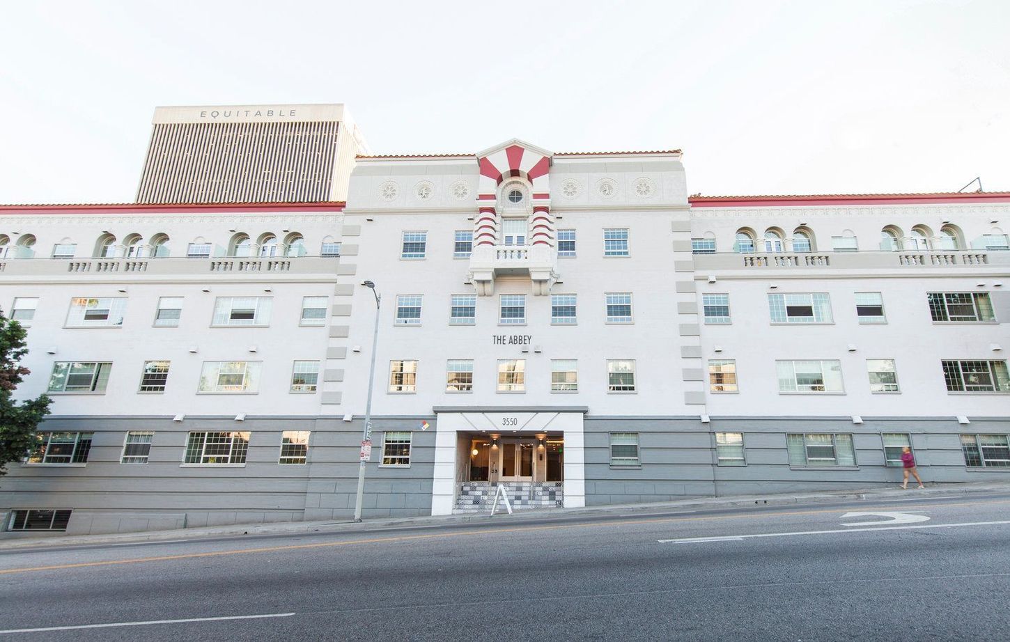White multi-story apartment building with red accents, set on a city street.