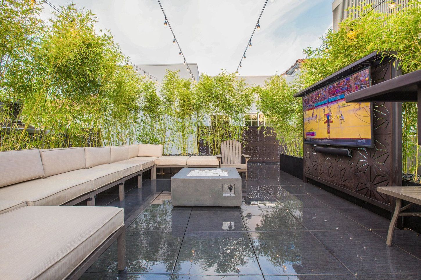 Rooftop patio with bamboo, sectional seating, fire pit, and a television.
