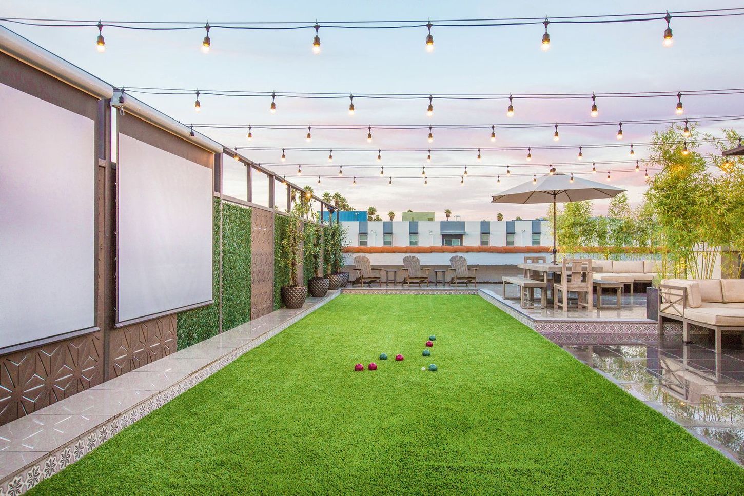 Rooftop patio with string lights, artificial turf lawn for lawn bowling, seating areas, and a retractable screen.