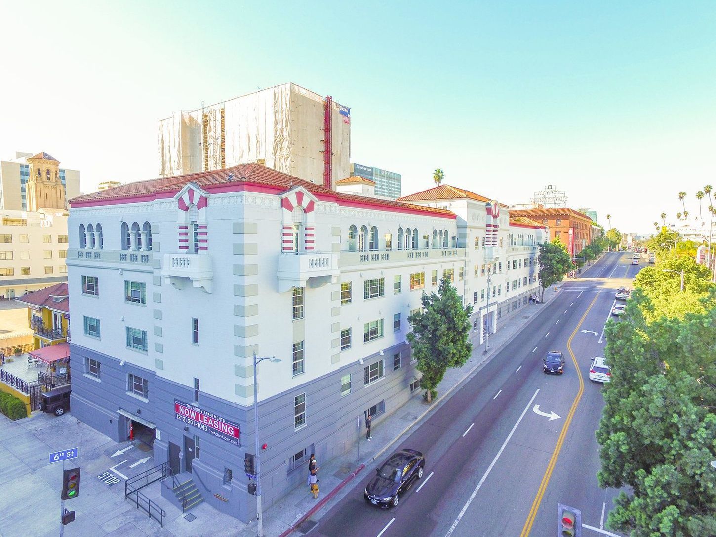 Multi-story building with white and gray facade, red accents, and street view.