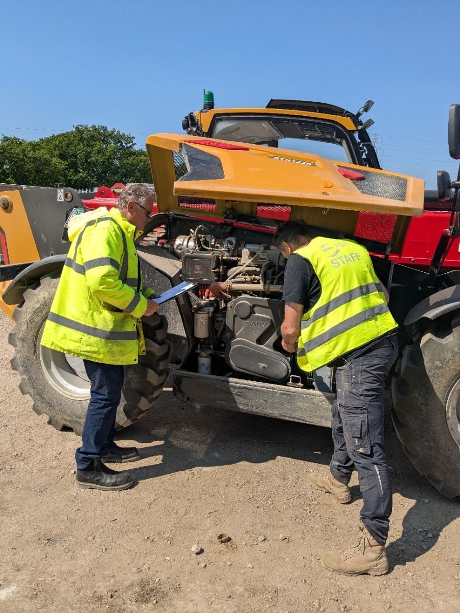 Two men are working on a telehandler