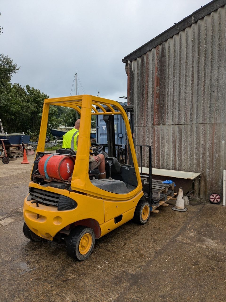A man is driving a yellow forklift in a parking lot