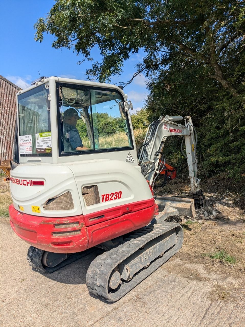 A red and white excavator is parked on the side of the road.