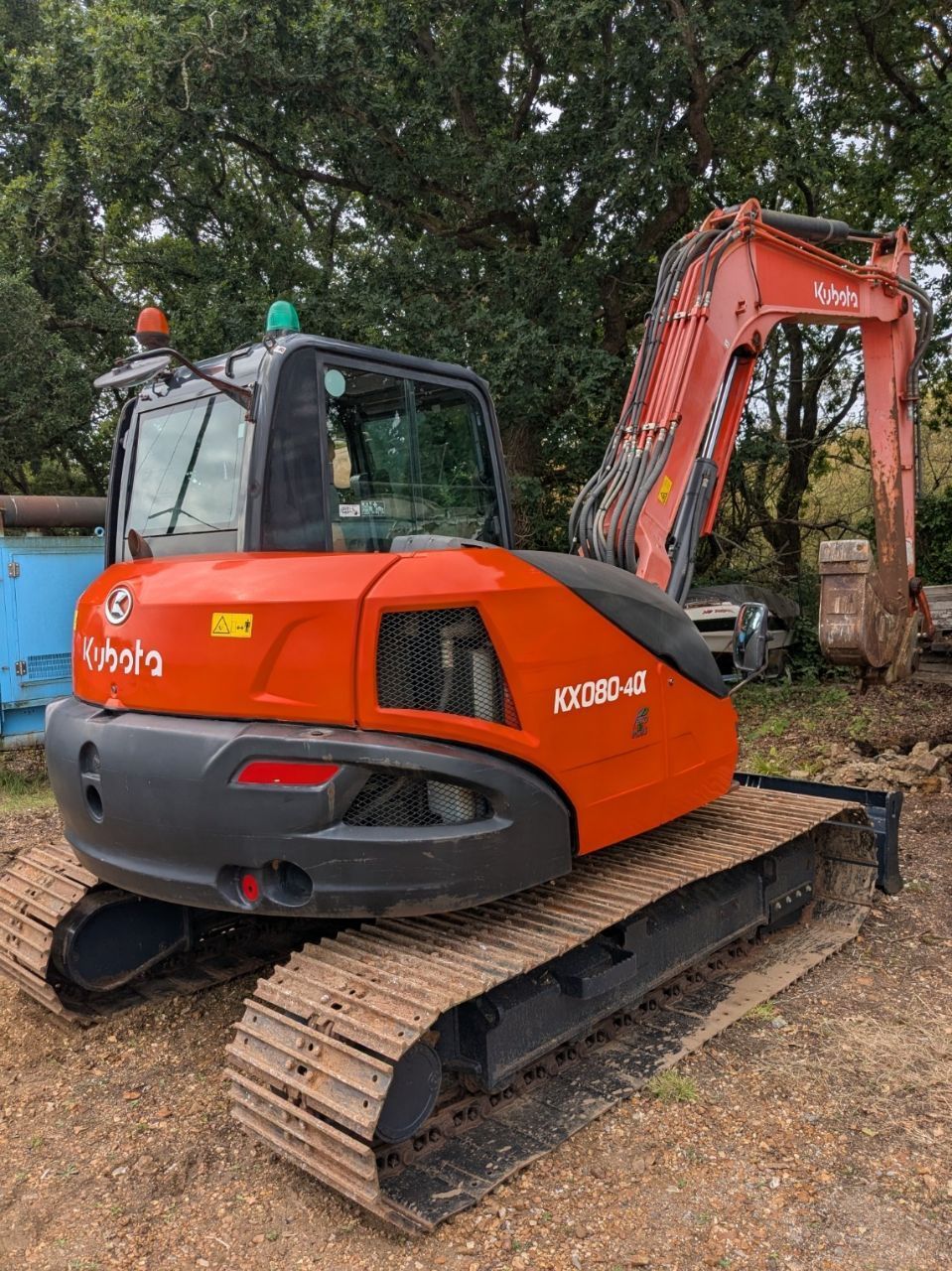 An orange and black excavator is parked in a dirt field.