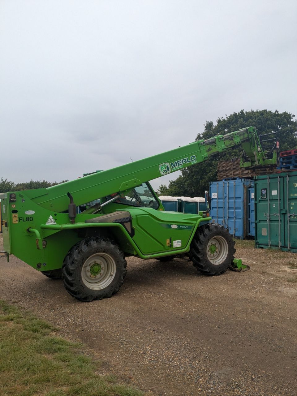 A green forklift is parked on the side of a dirt road.