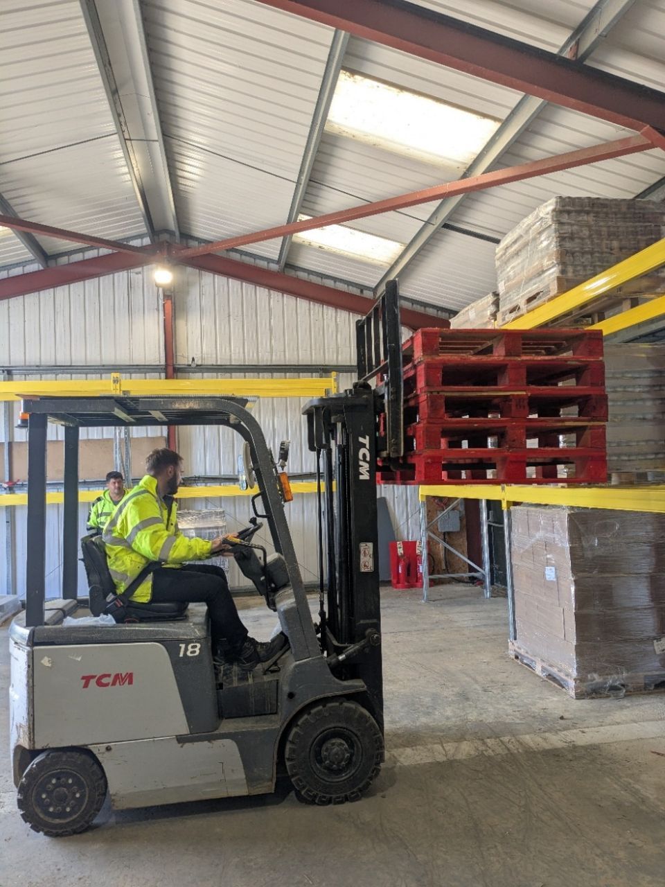 A man is driving a forklift in a warehouse.