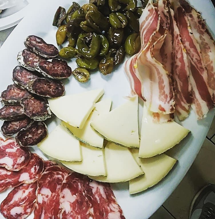 Un piatto bianco condito con carne, formaggio e peperoni
