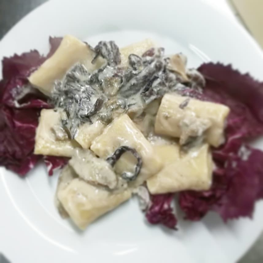 Un piatto bianco con sopra pasta e lattuga viola