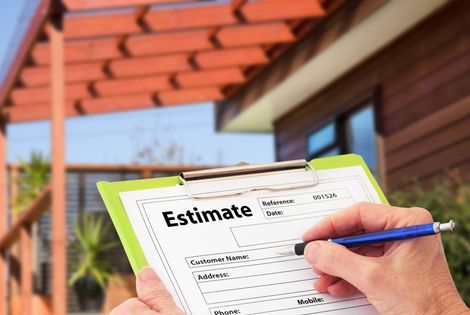 A person is holding a clipboard with an estimate on it in front of a house.