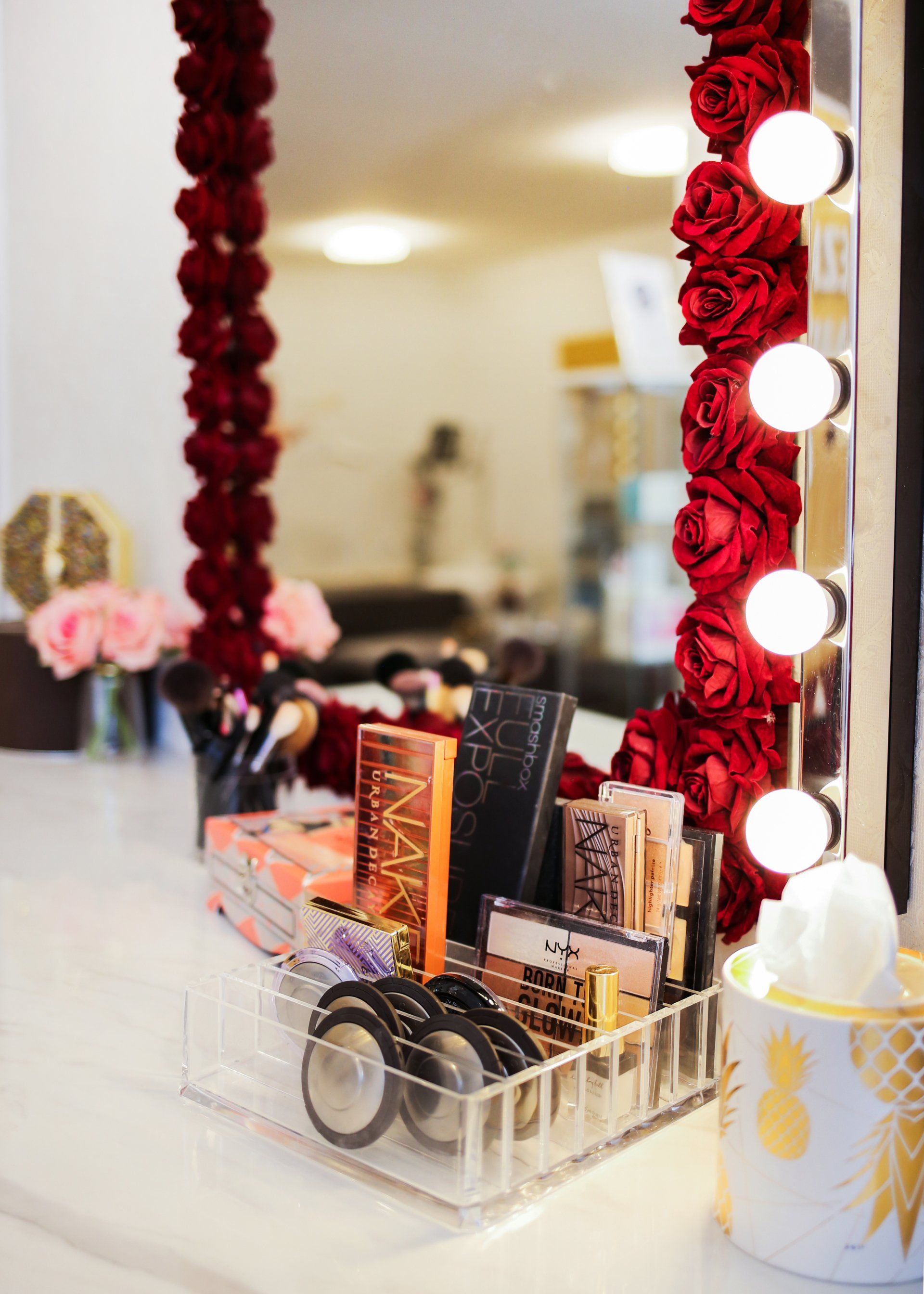 Ein Schminktisch mit Spiegel und Beleuchtung und einer Ablage mit Schminktablett.