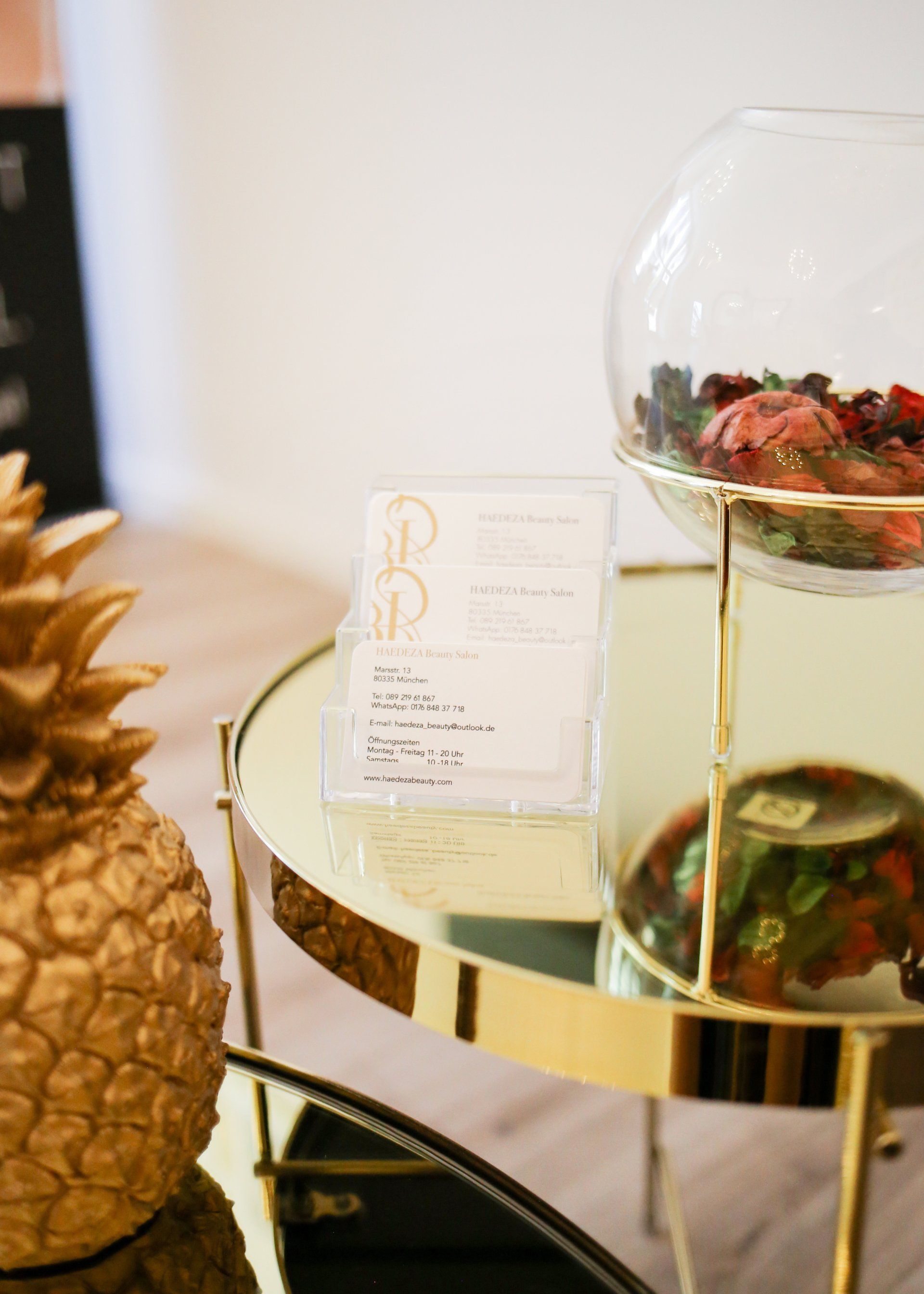 Auf einem Tisch steht eine Ananas neben einer mit Früchten gefüllten Glasschale.