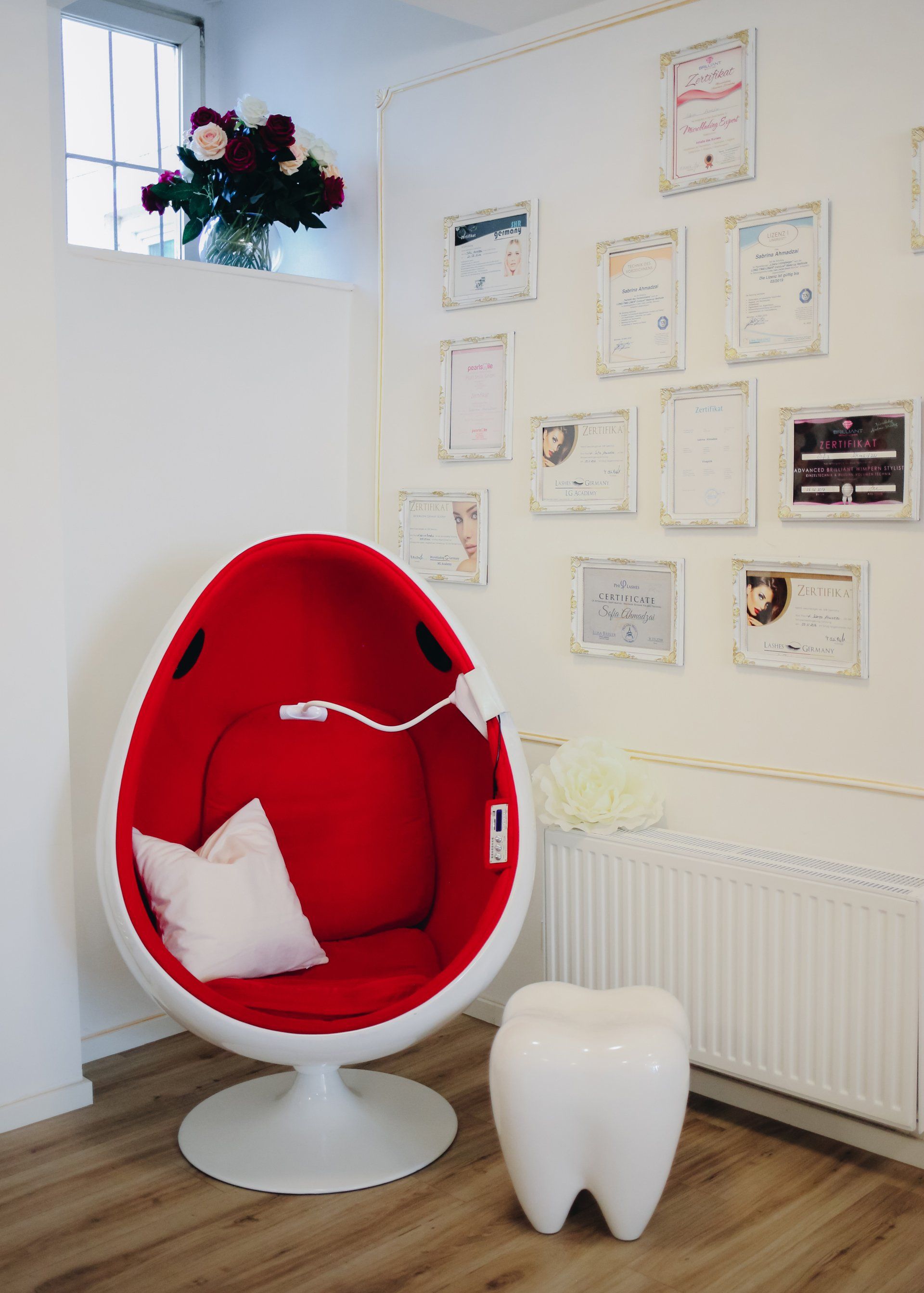 In einem Raum steht ein roter Stuhl neben einem weißen Zahnhocker.