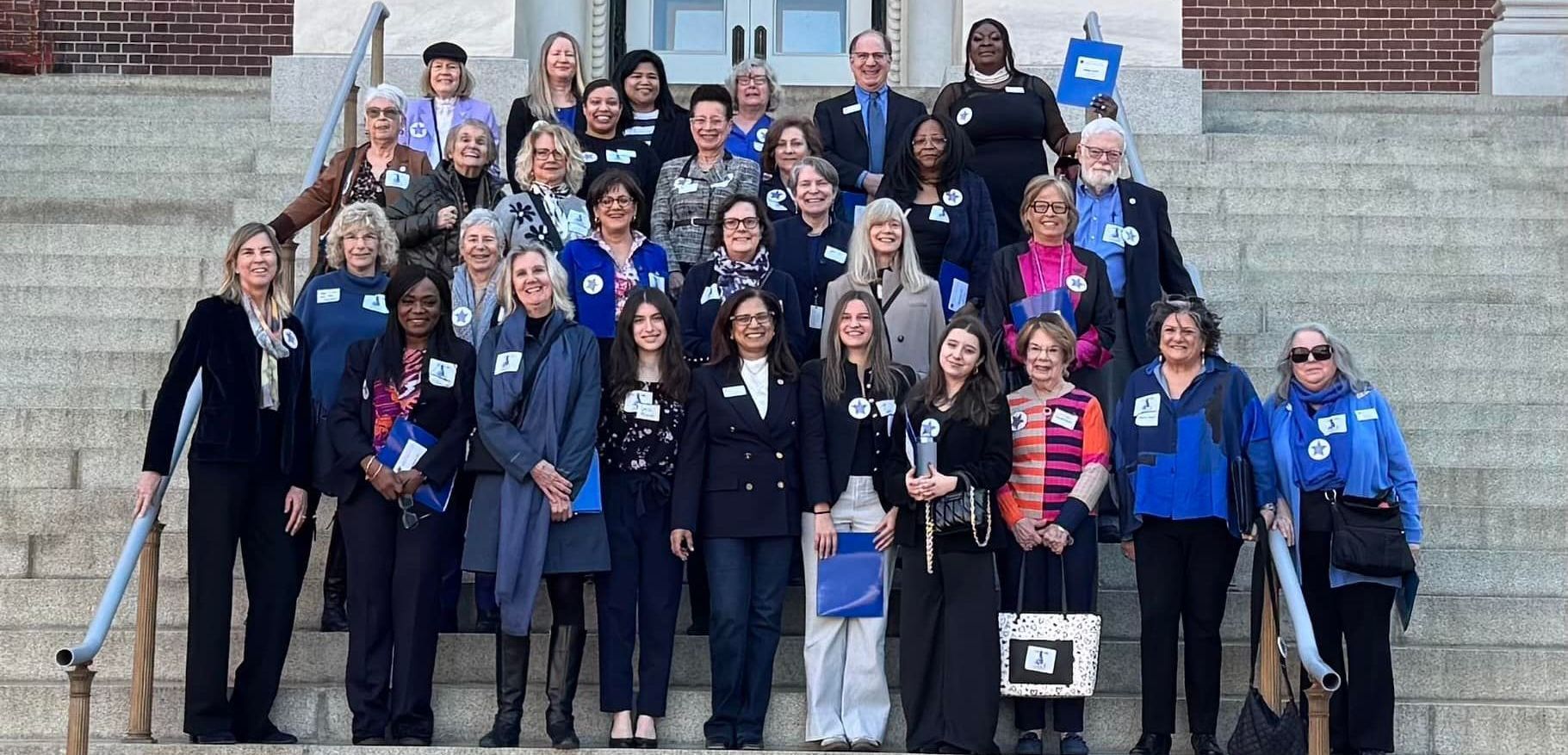 Group photo on Annapolis Capital steps; diverse people smiling, wearing nametags. Building in background.