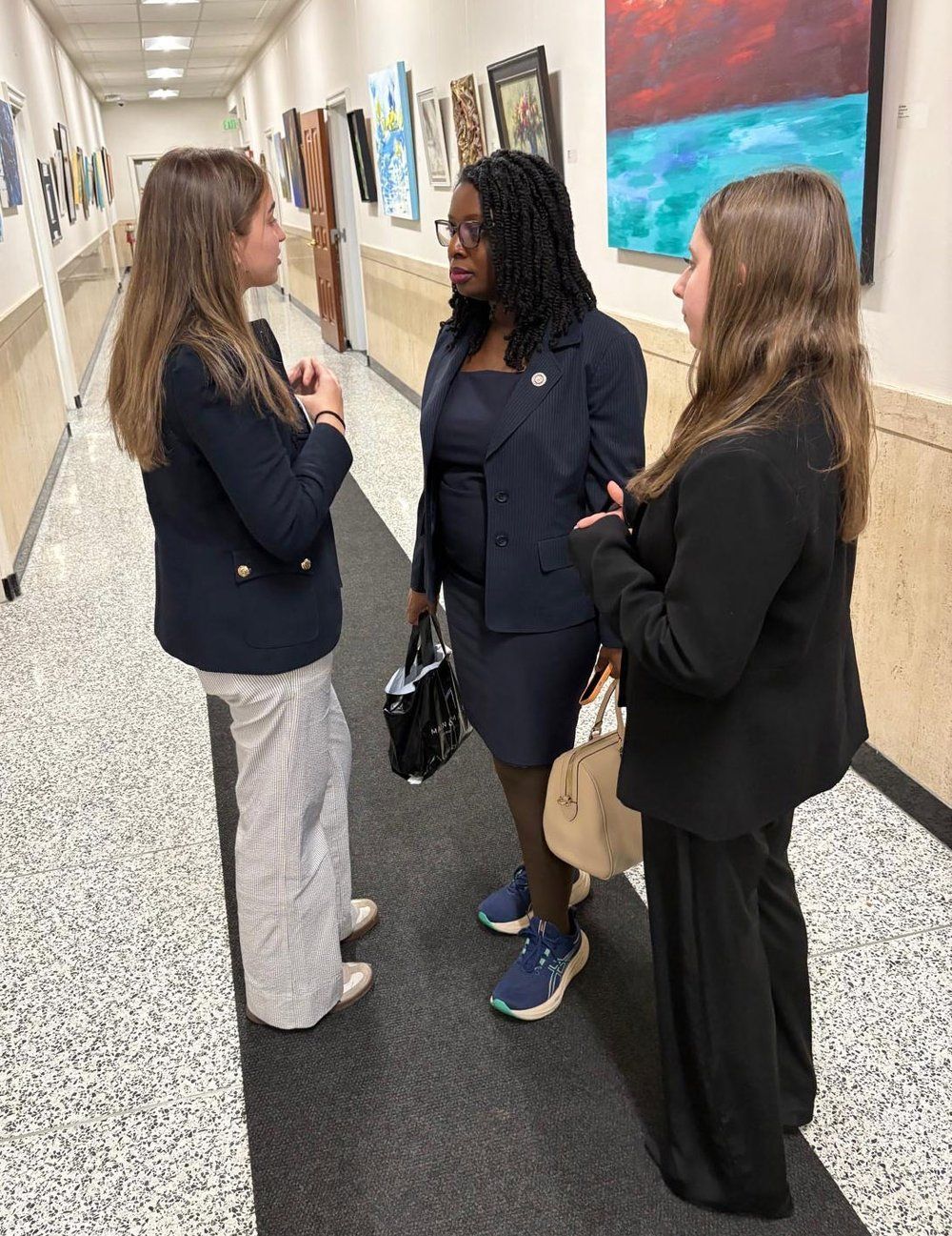 Three women in a hallway conversing. 