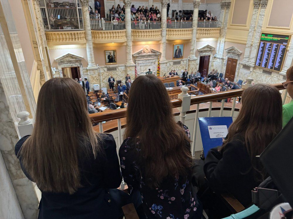 Three young women watching the legislative session from a balcony.