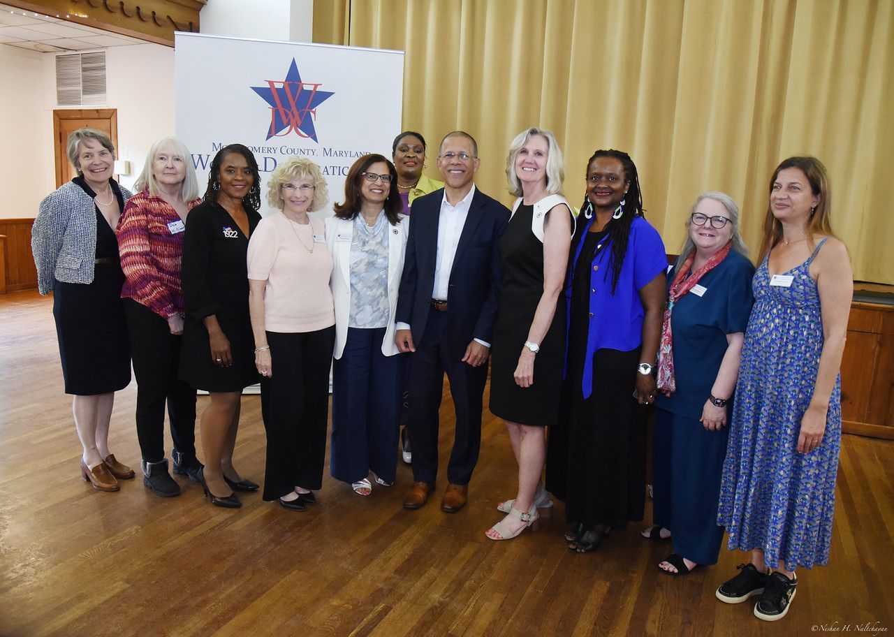 Group photo of diverse people in a room, smiling at the camera. A banner in the background has a star logo.