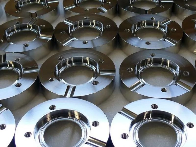 Metal gate with geometric design, reflecting surroundings, set between brick and concrete walls.