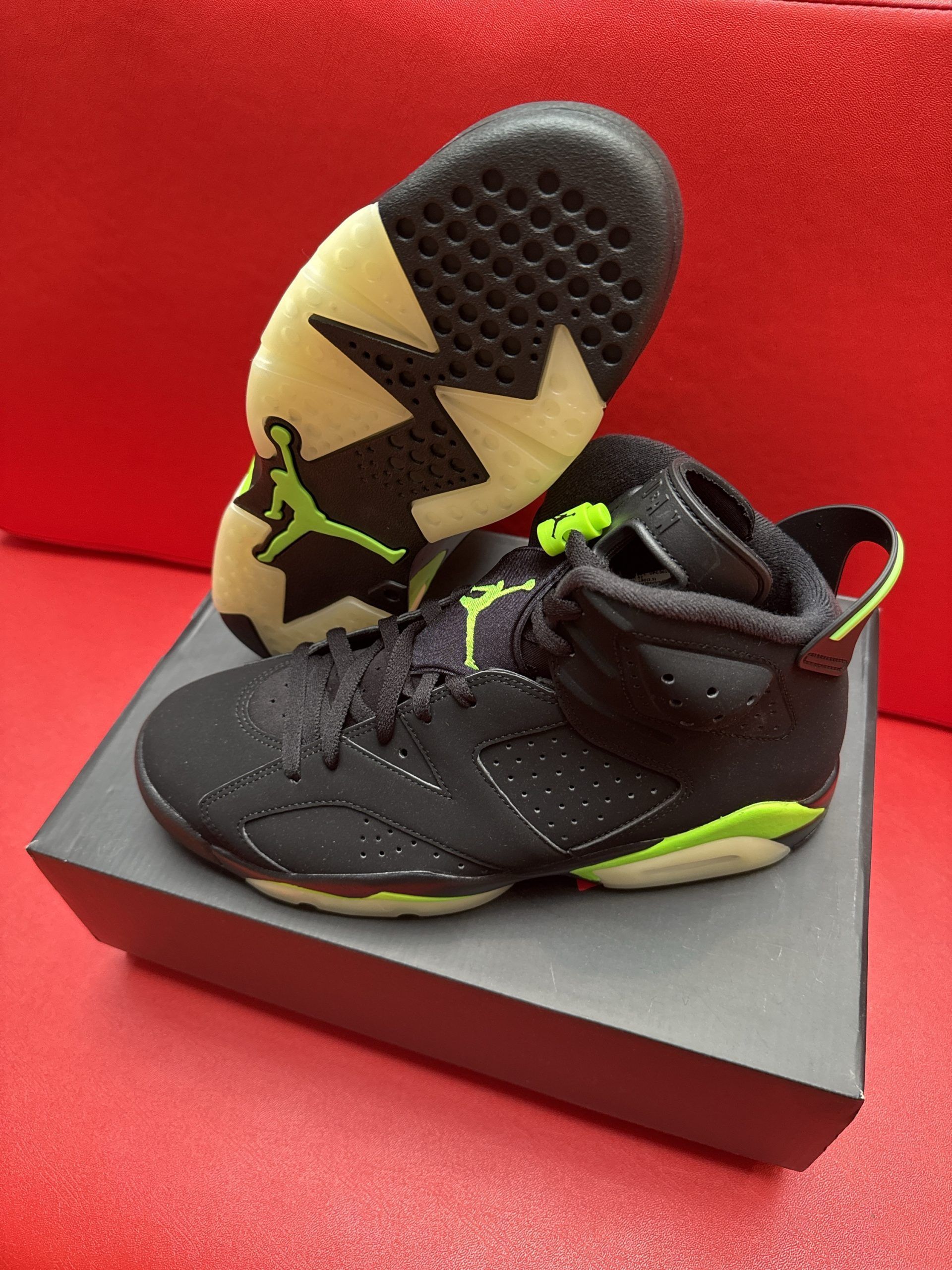 Black and green Air Jordan 6 sneakers on a box, with one sole facing up.
