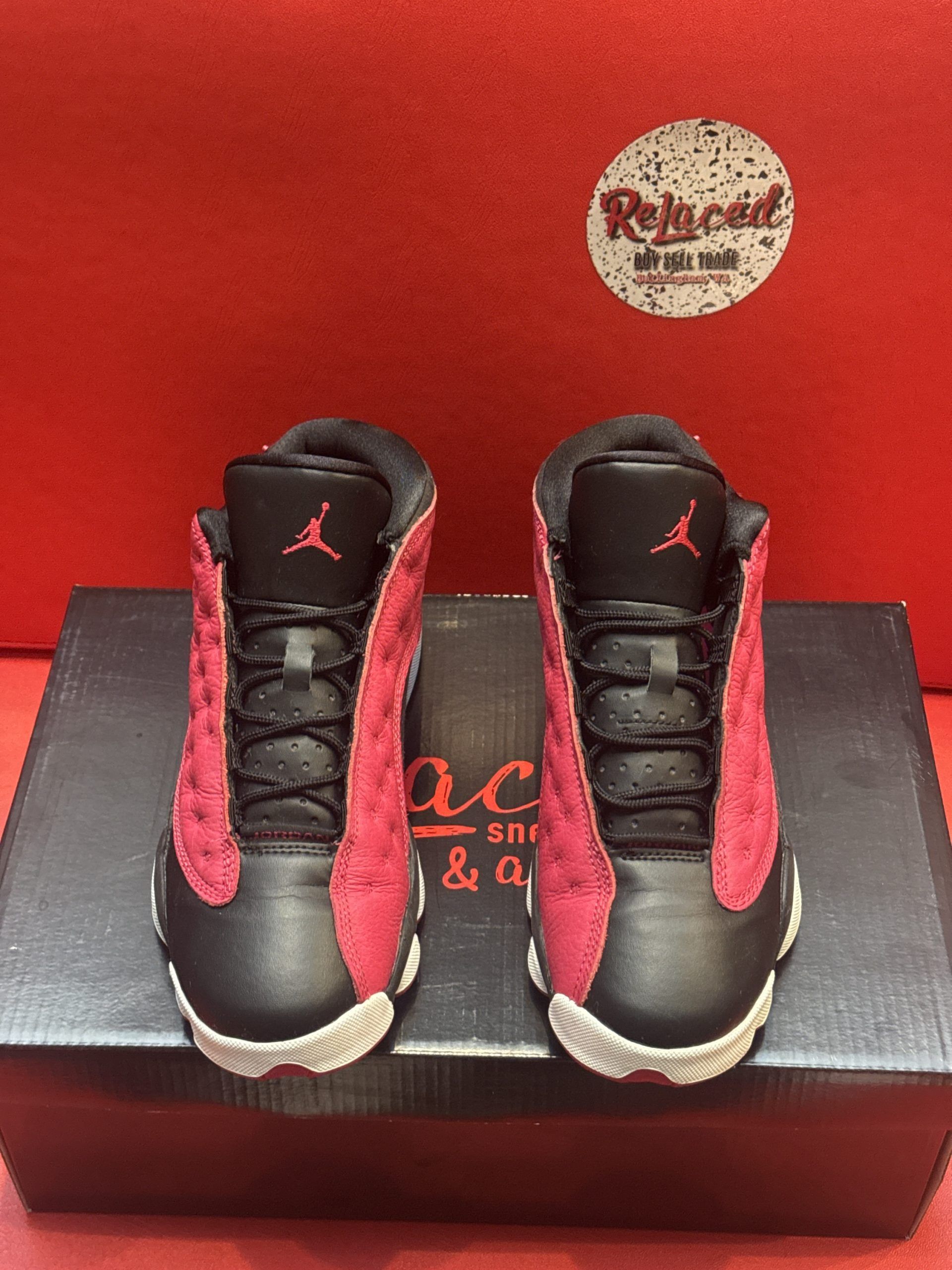 Red and black Air Jordan 13 sneakers on a shoebox, with the sole visible.