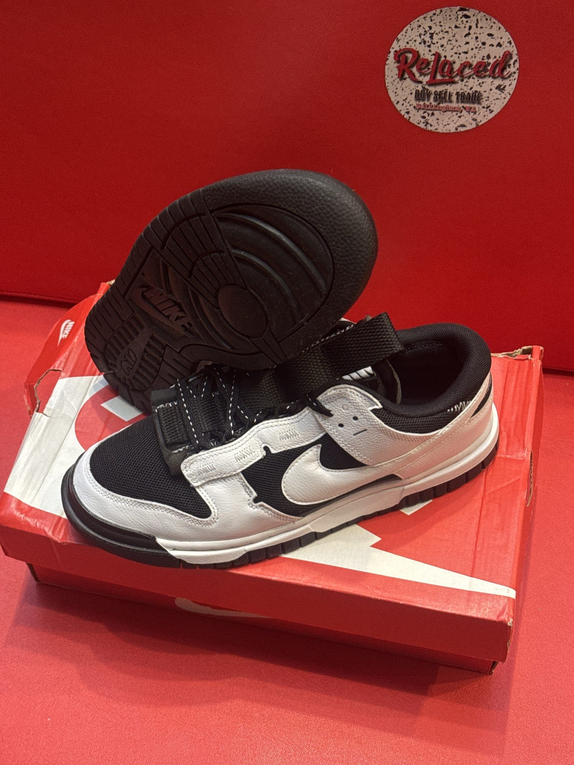 Nike Dunk Low sneakers, black and white, on top of a red shoe box.
