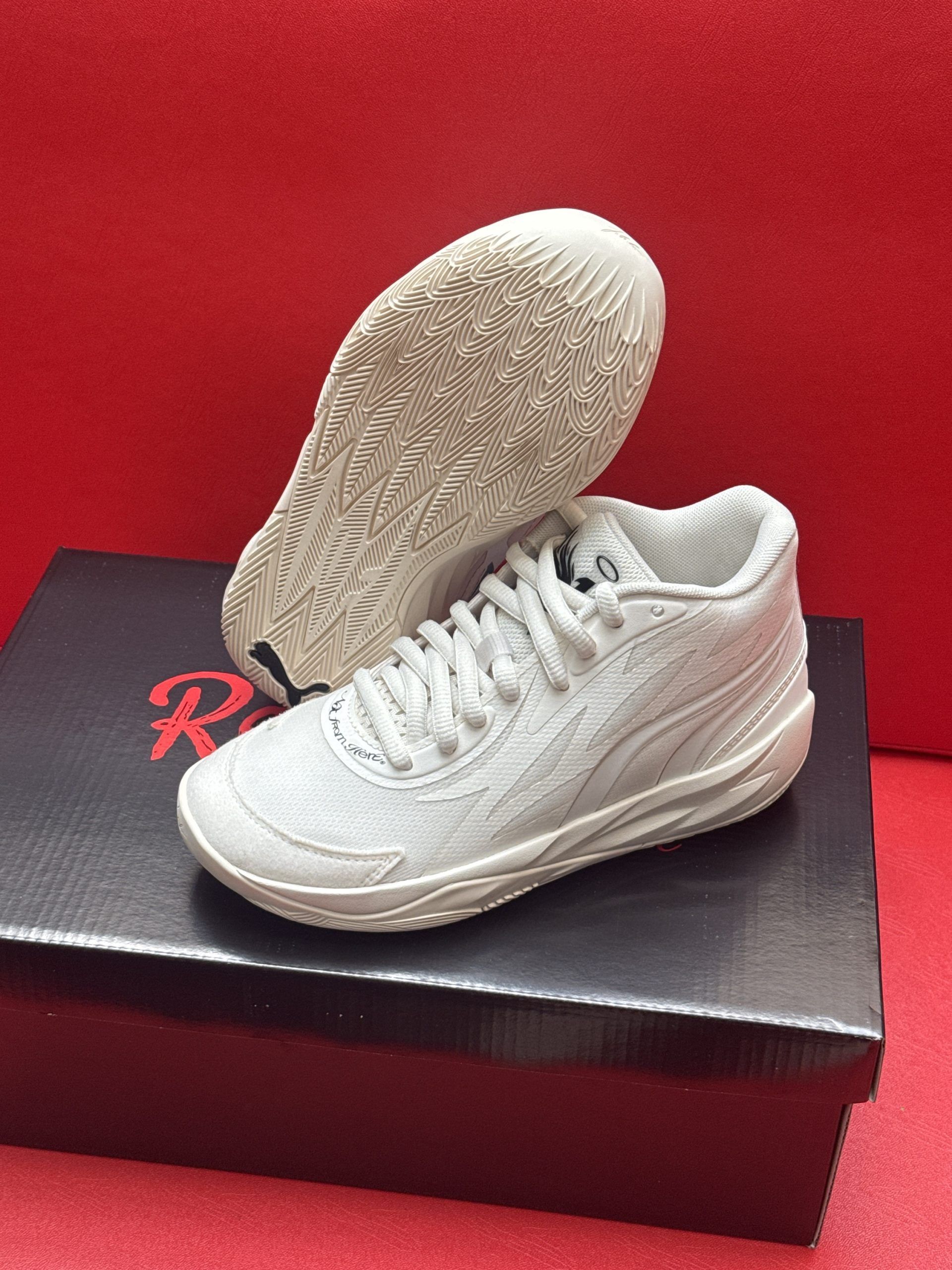 White sneaker with textured sole atop a shoe box on a red background.