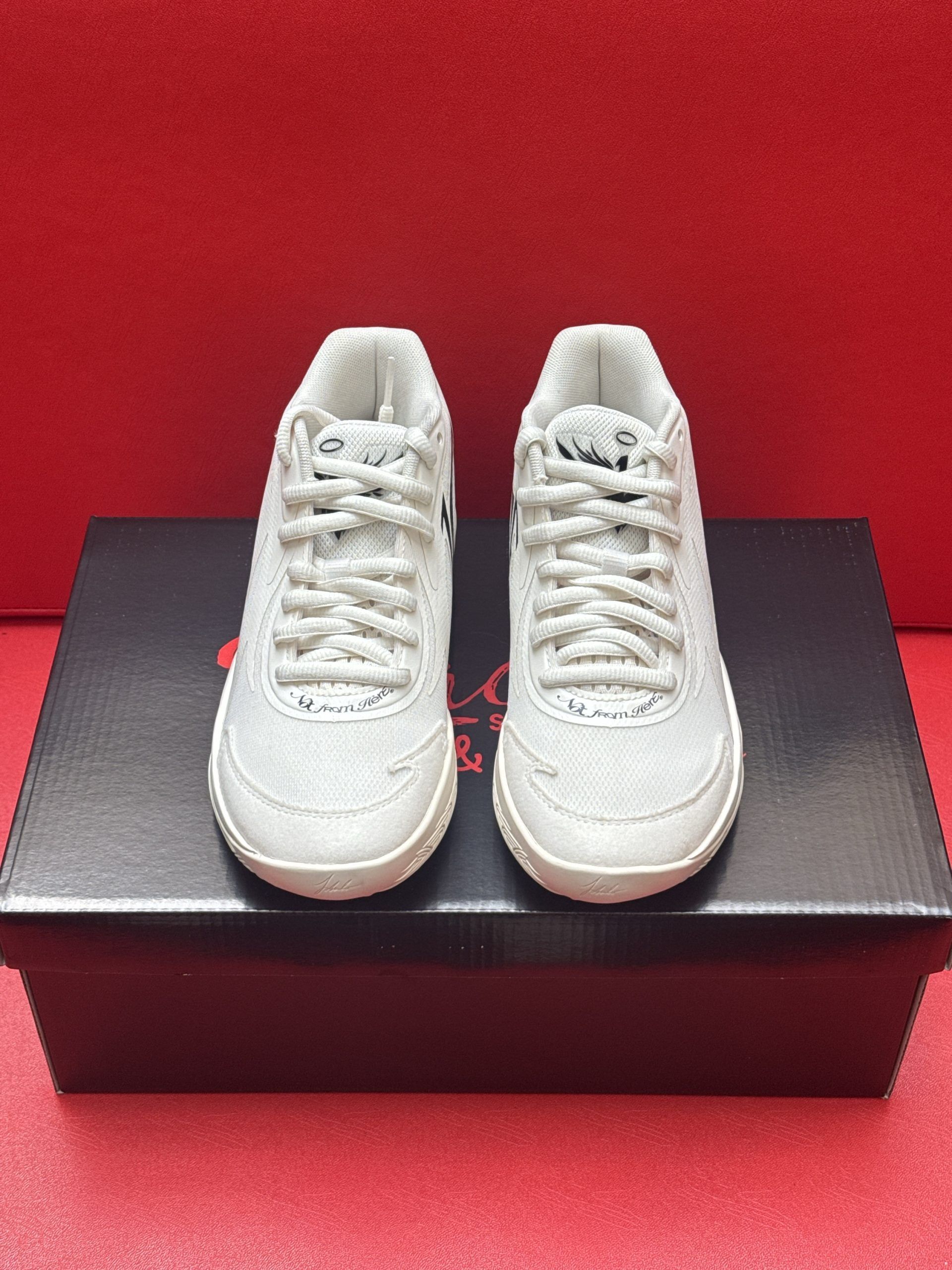 White sneaker with textured sole atop a shoe box on a red background.