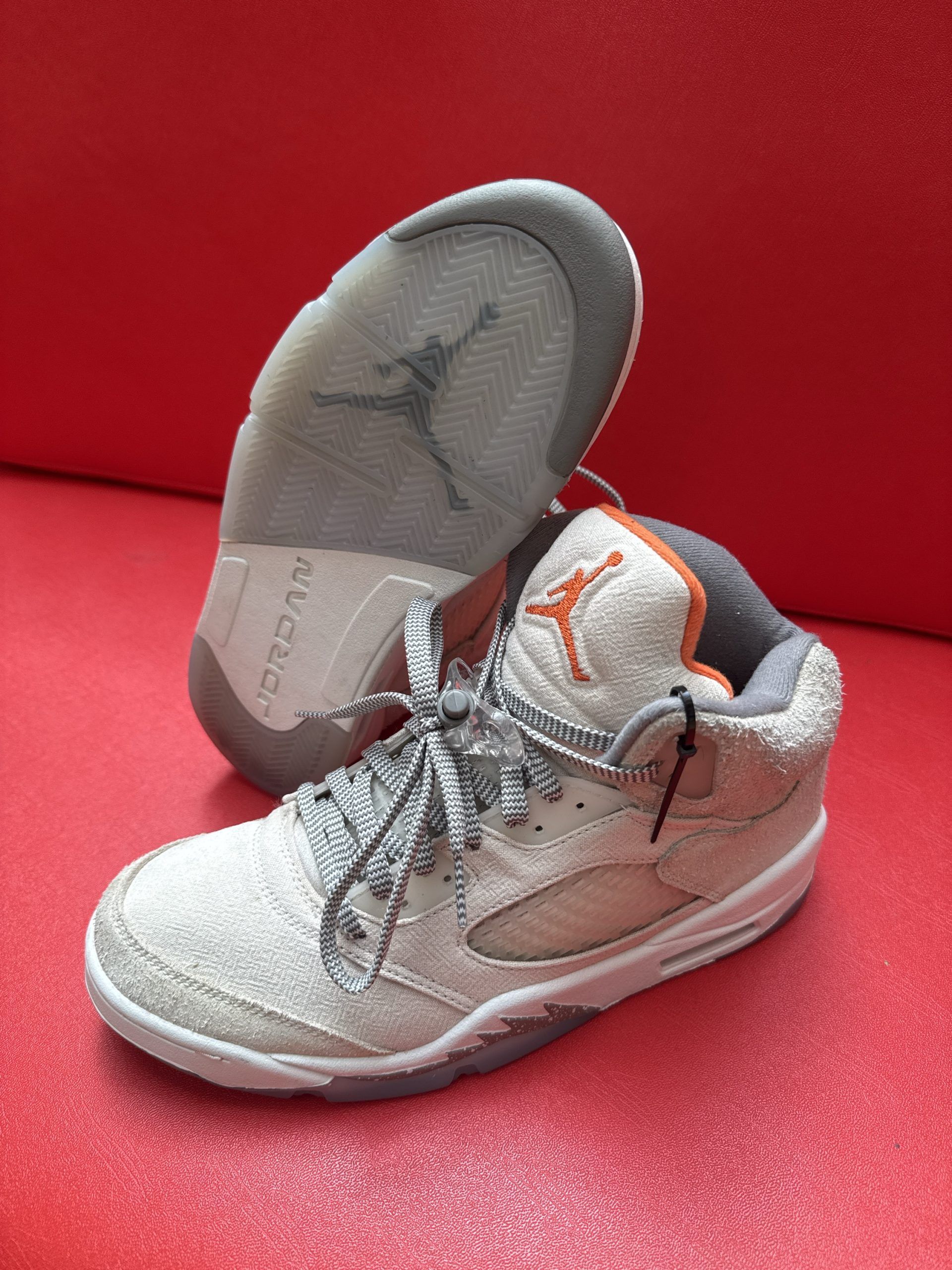 Pair of light tan and orange Air Jordan 5 sneakers with gray soles.