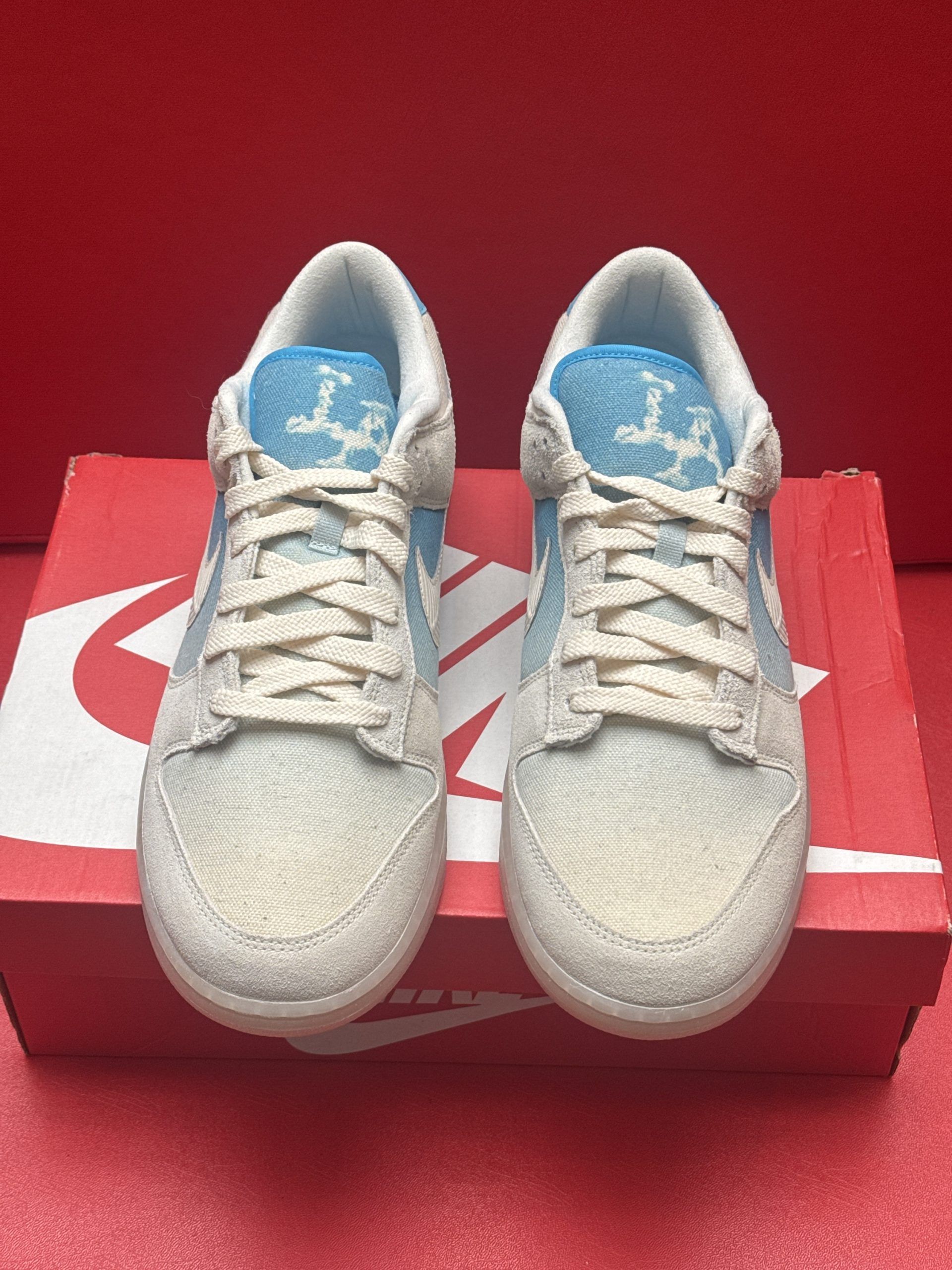 Nike Dunk Low sneakers, light blue and cream colors, displayed on an orange Nike shoe box.