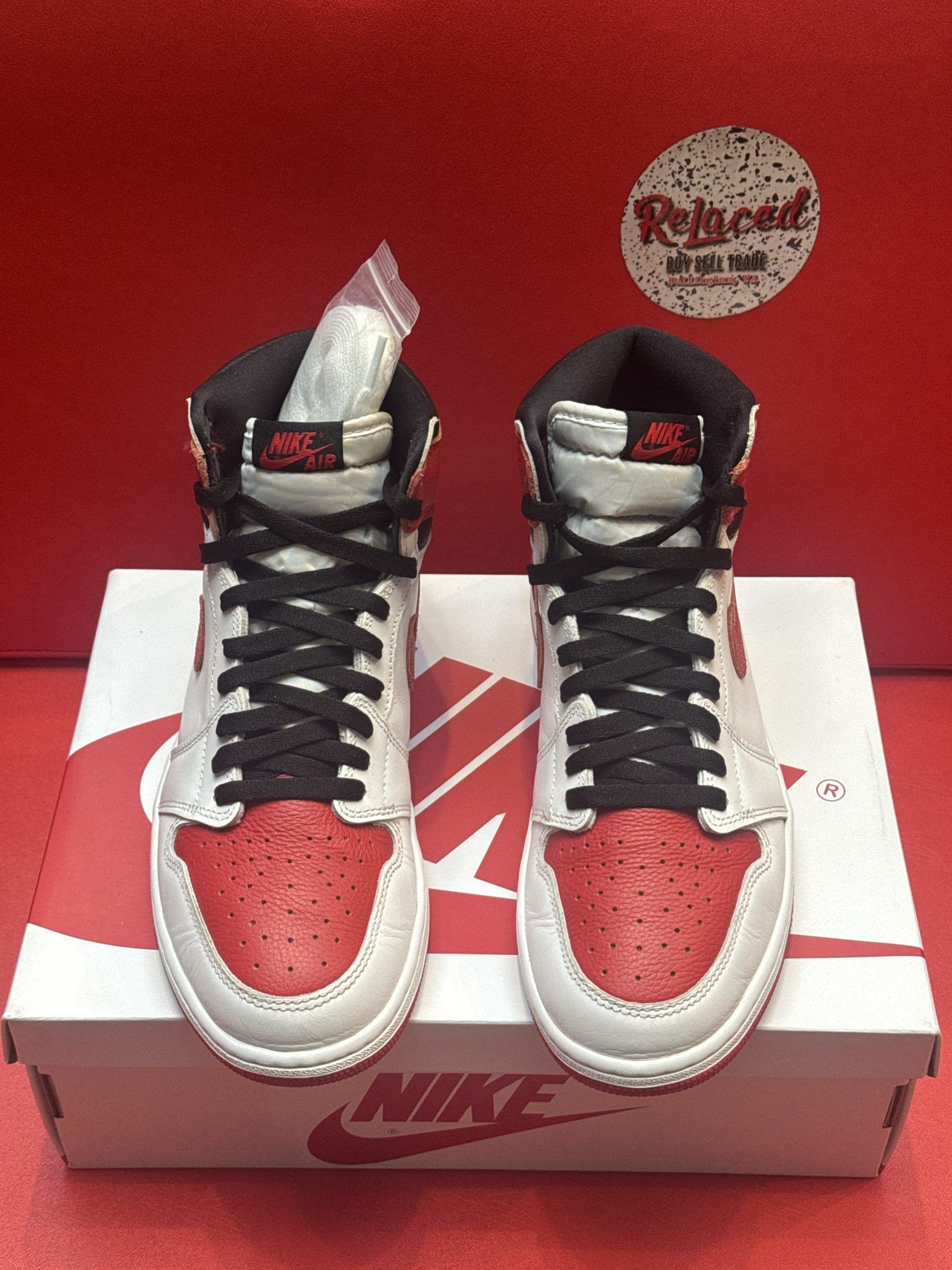 Red and white Air Jordan 1 sneaker on a white box with a red sole displayed.