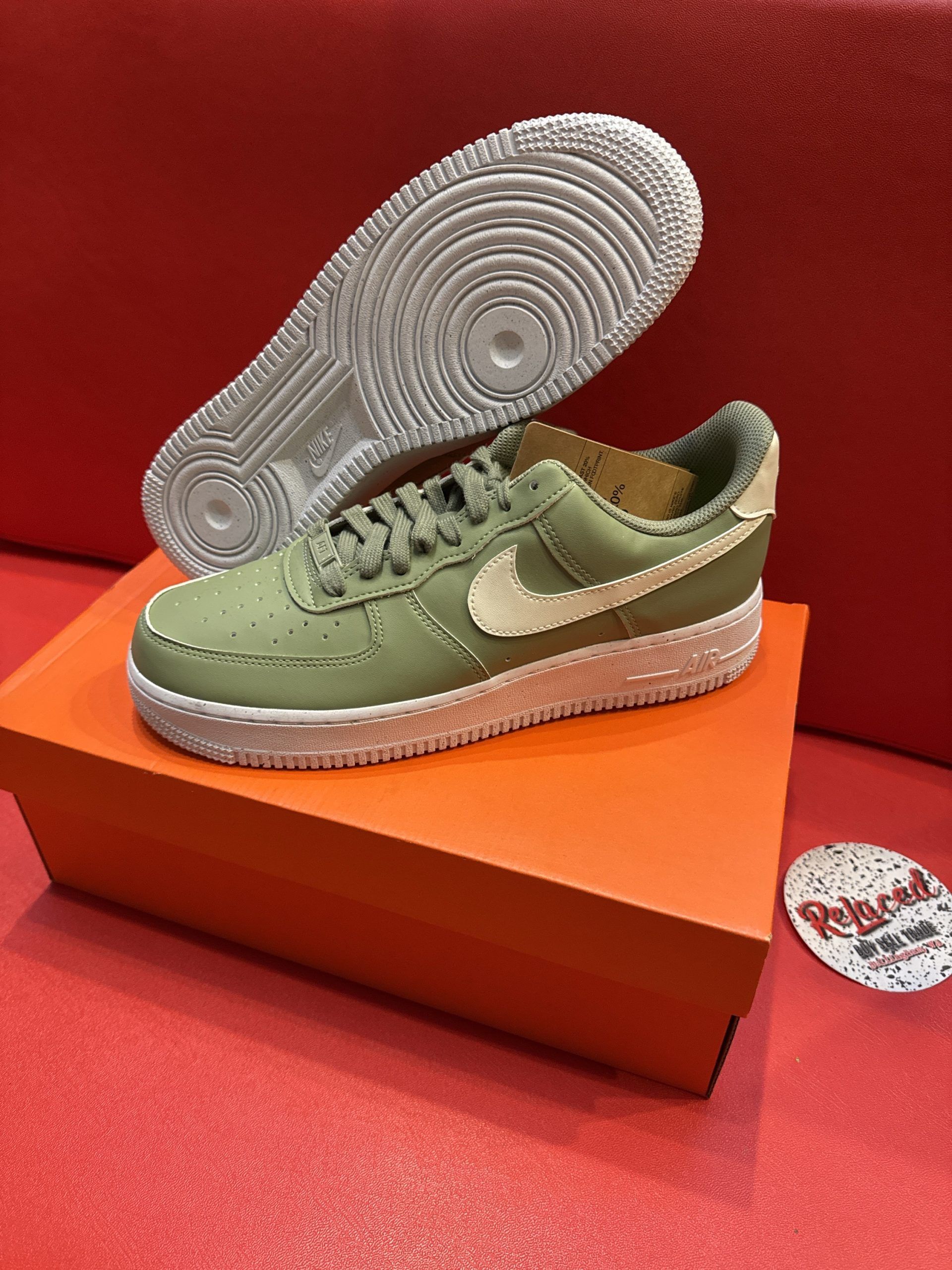 Green Nike Air Force 1 sneakers on orange box, white sole, against red background.