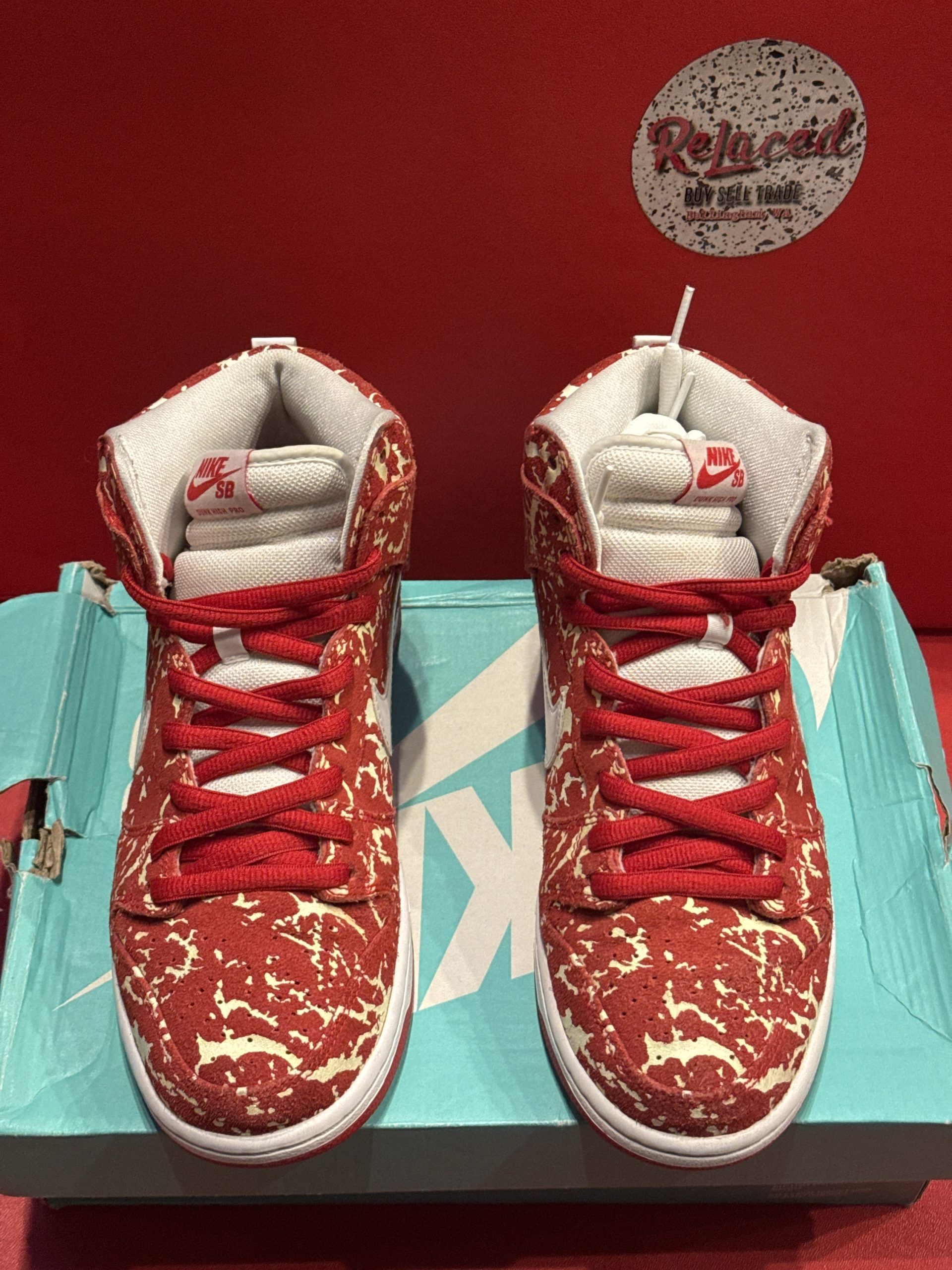 Red and white Nike Dunks on a turquoise shoe box, against a red backdrop.