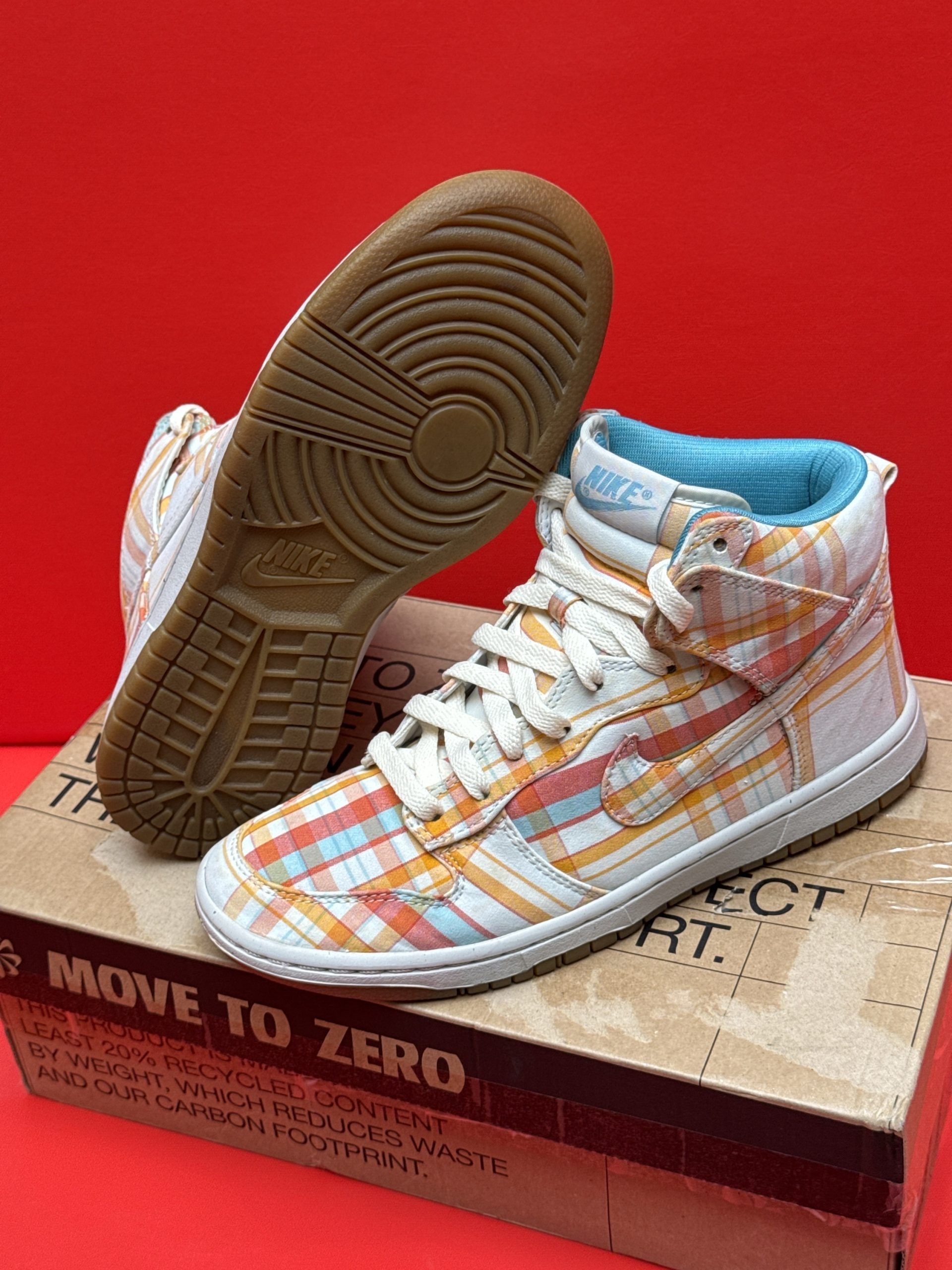 Nike high-top sneakers with a plaid pattern in orange, red, and blue on a box.