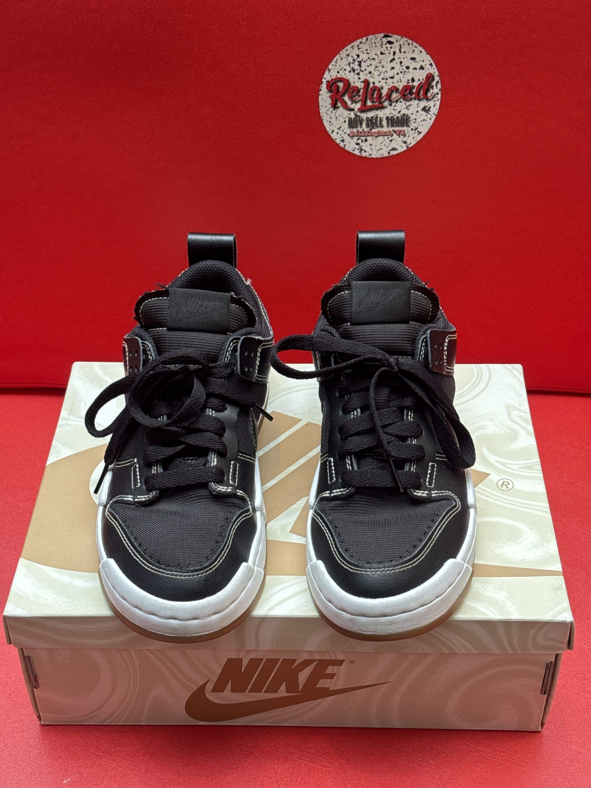 Black Nike sneakers with white soles and a brown outsole, on a Nike box.