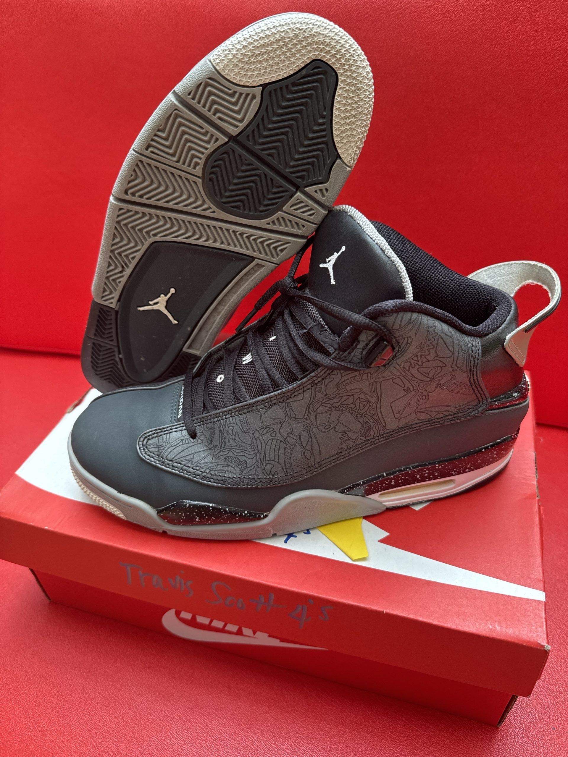Black and grey Air Jordan sneakers, with the sole visible, on a red shoebox.