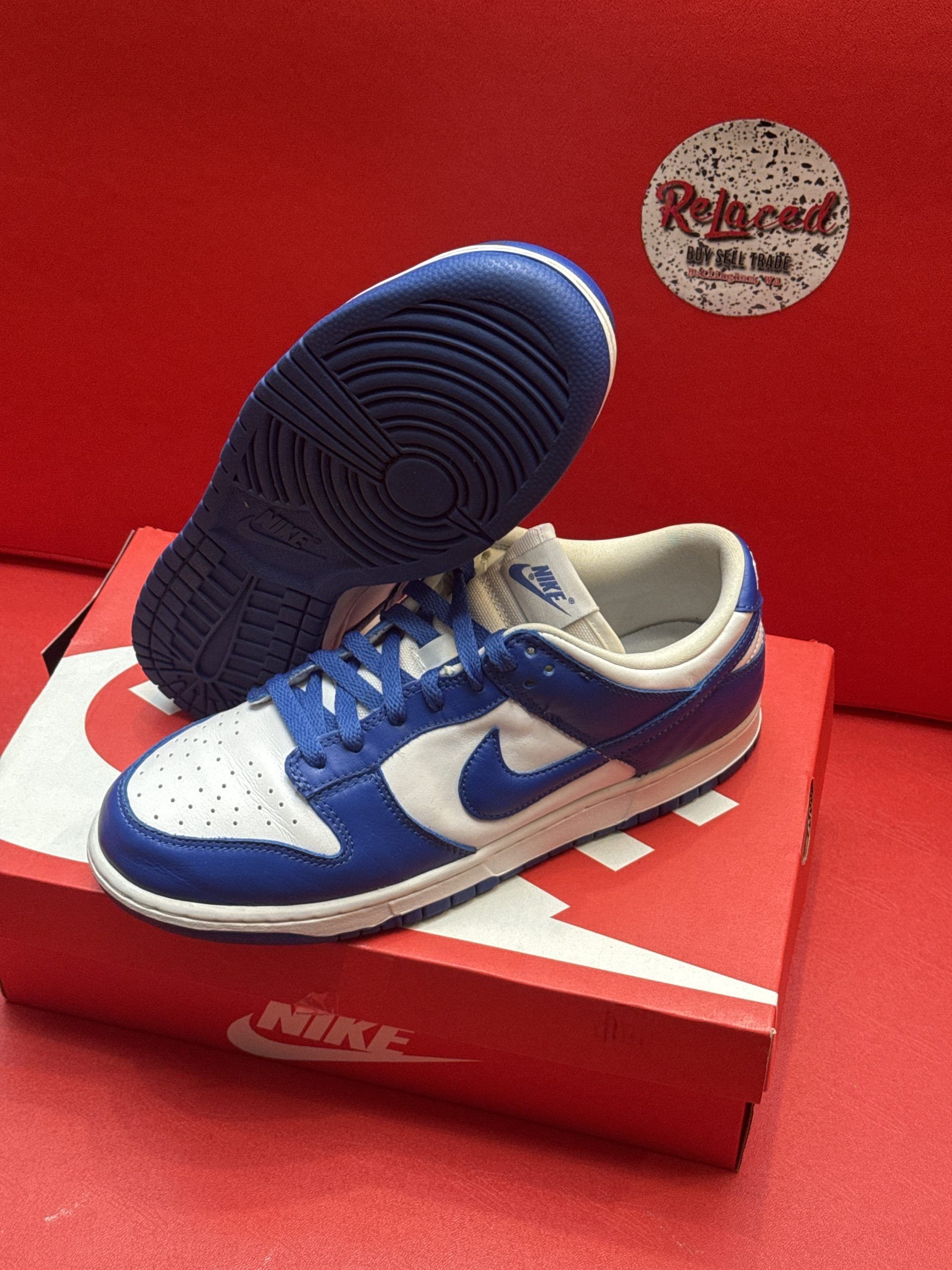 Blue and white Nike Dunk Low shoes on a red Nike box, with a blue sole visible.