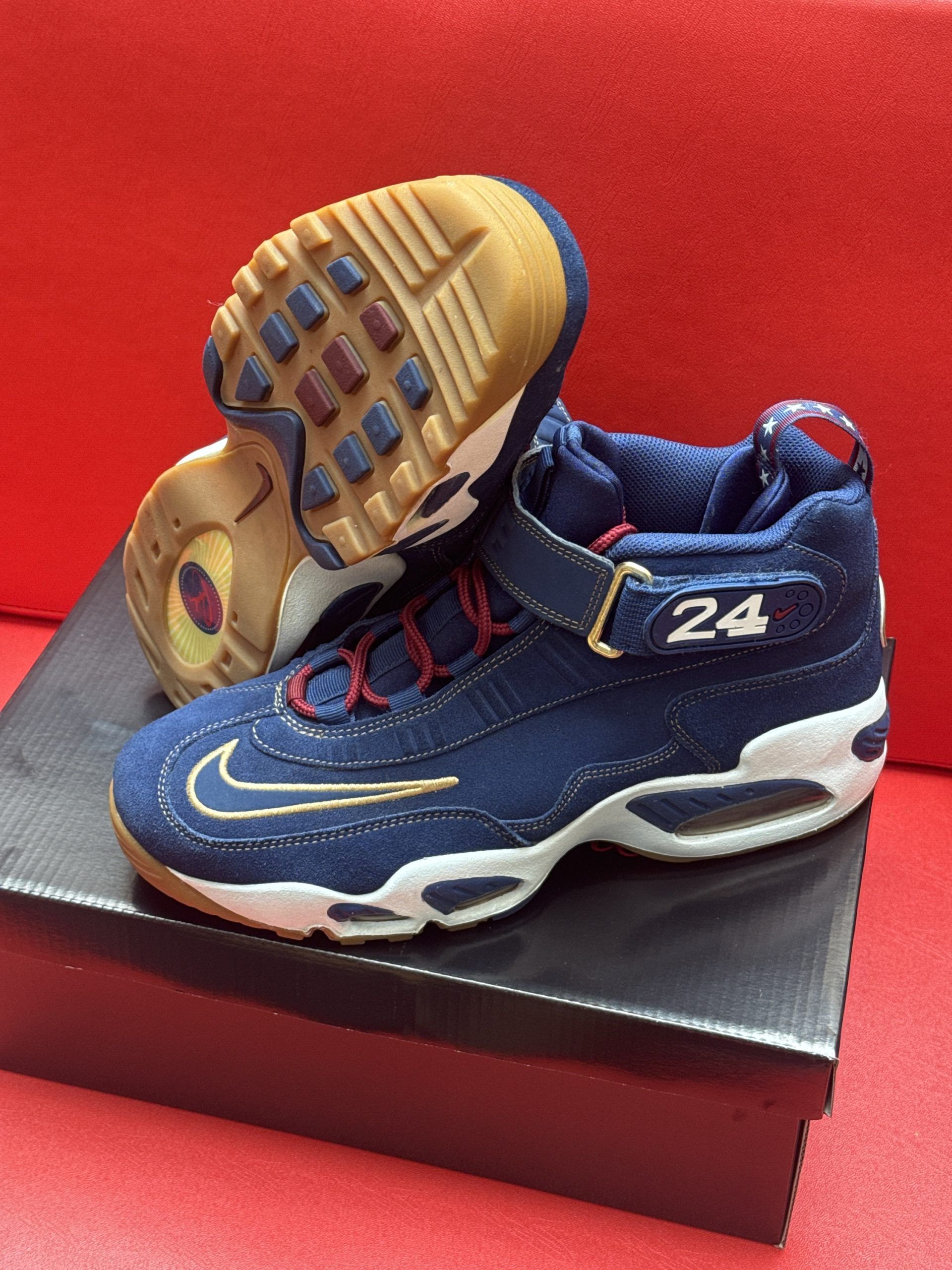 Blue and white Nike toddler sneakers with a gold swoosh and brown sole, resting on a box.