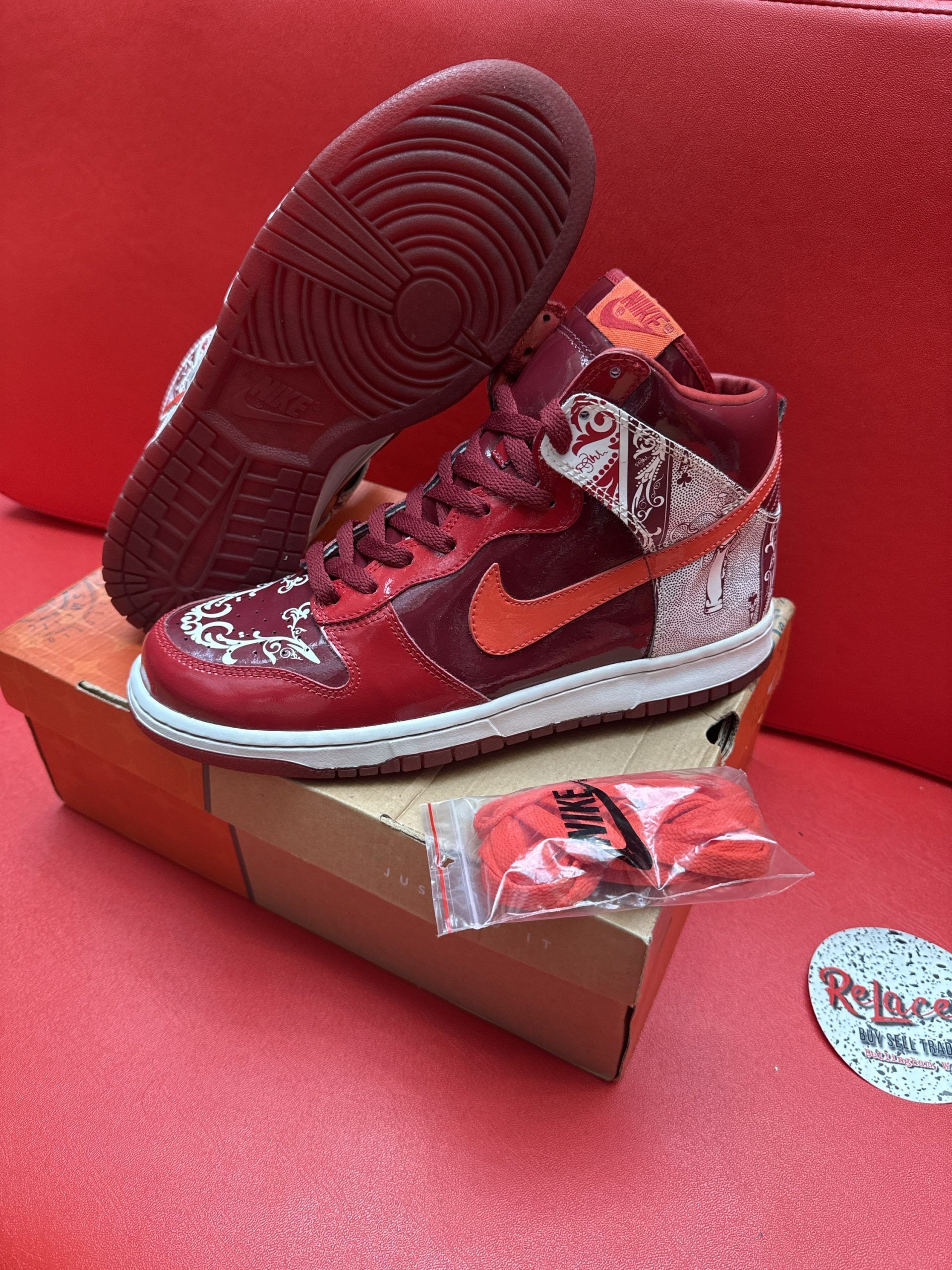 Red Nike Dunks, box, and extra laces on a red surface.