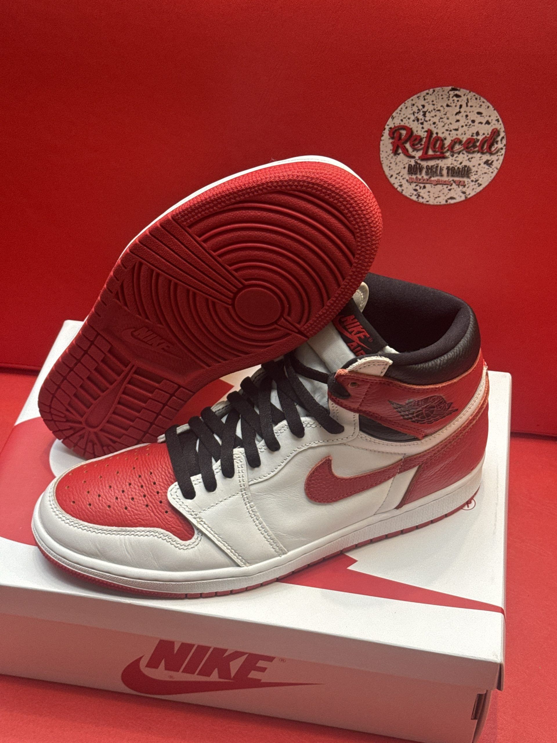 Red and white Air Jordan 1 sneaker on a white box with a red sole displayed.