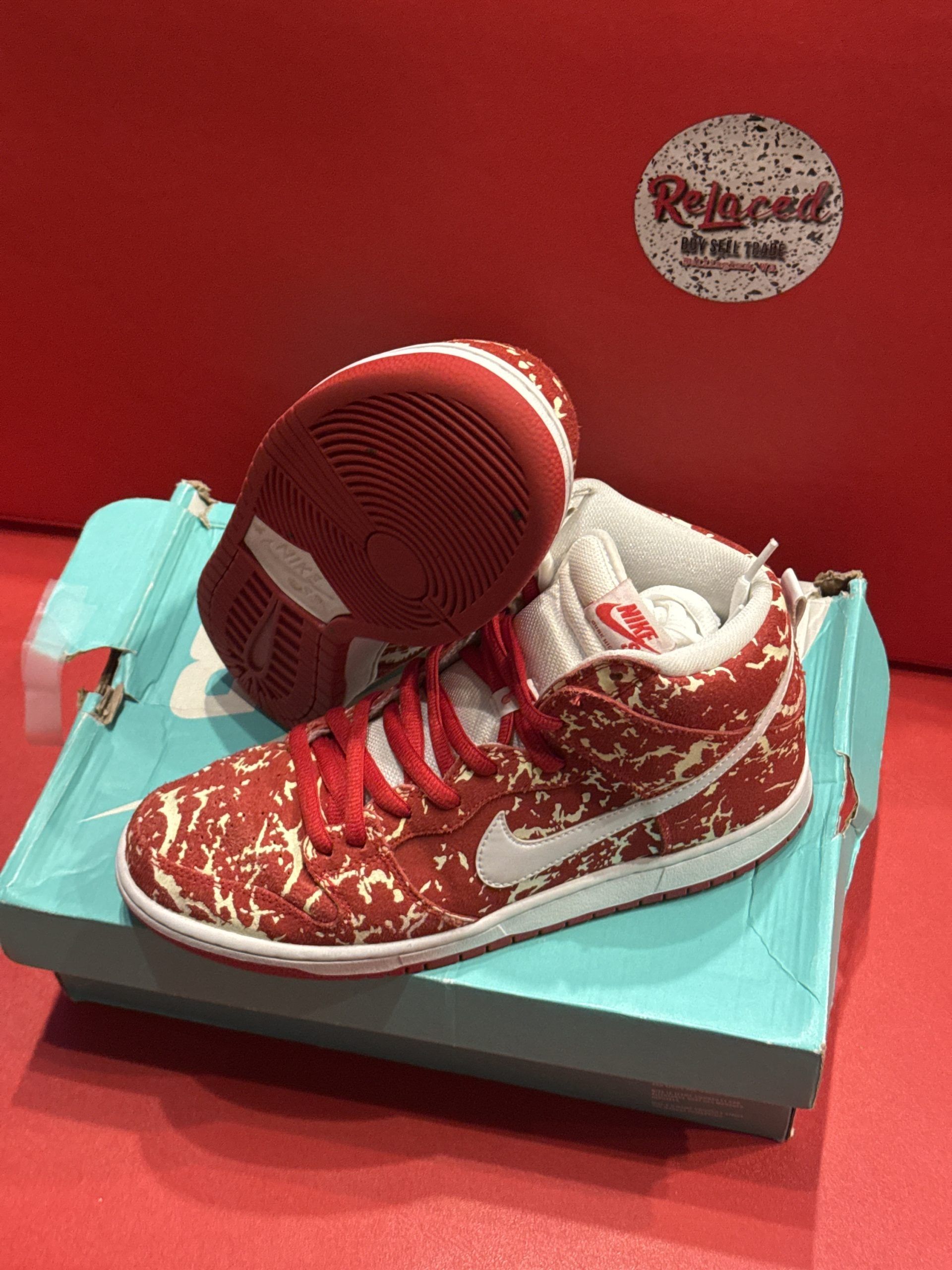 Red and white Nike Dunks on a turquoise shoe box, against a red backdrop.
