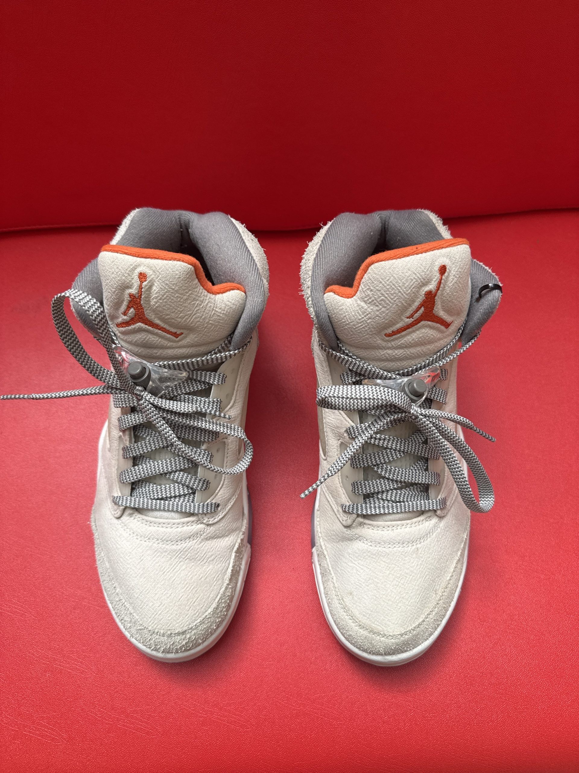 Pair of light tan and orange Air Jordan 5 sneakers with gray soles.