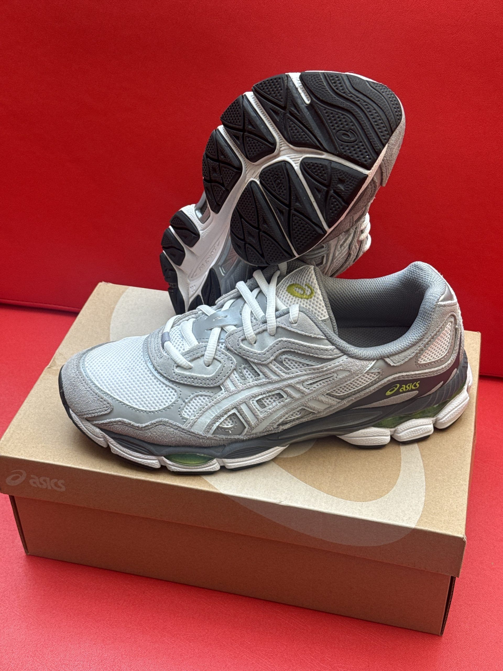 Silver and gray Asics running shoe on a box, sole of second shoe visible.