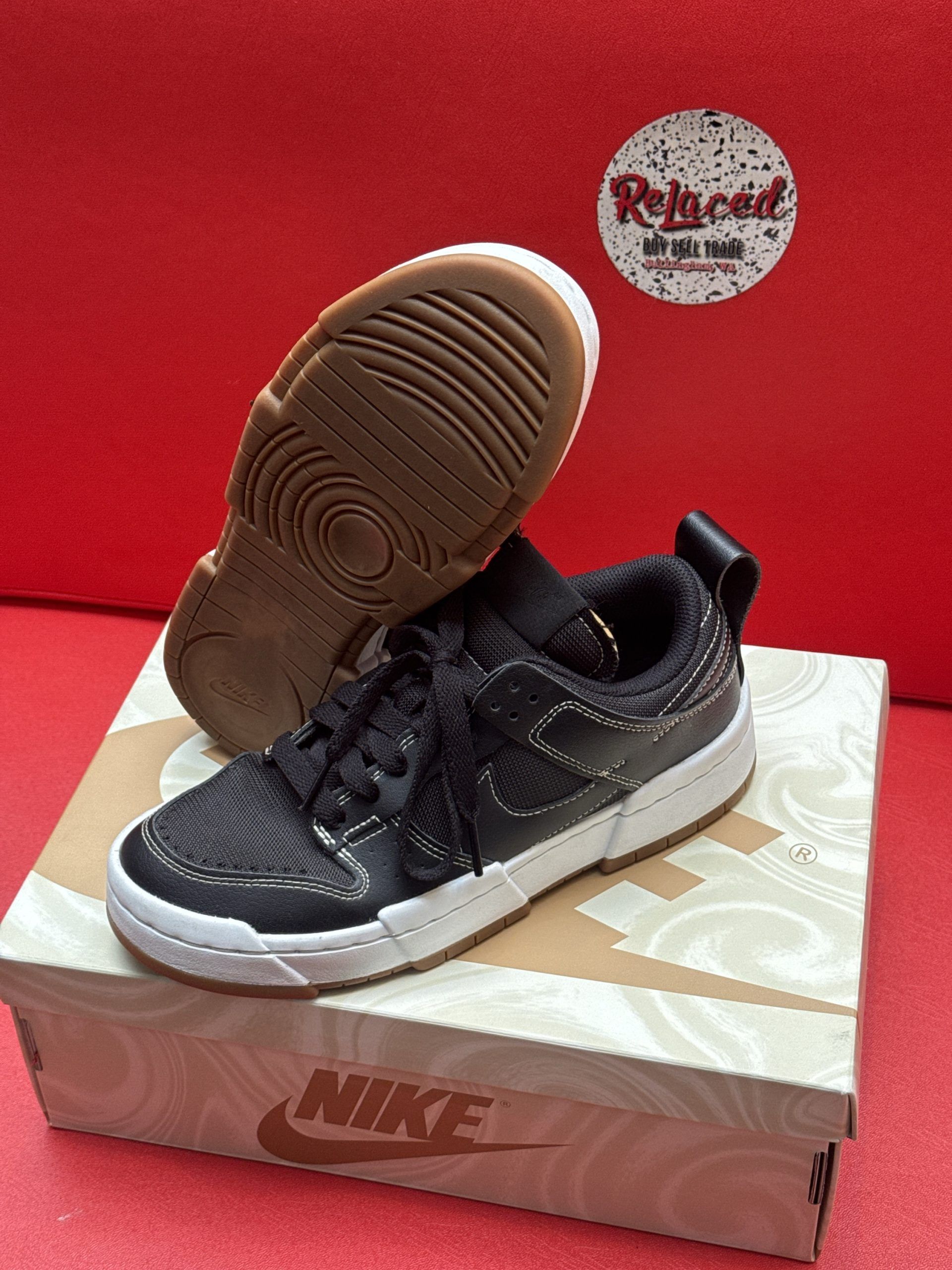 Black Nike sneakers with white soles and a brown outsole, on a Nike box.