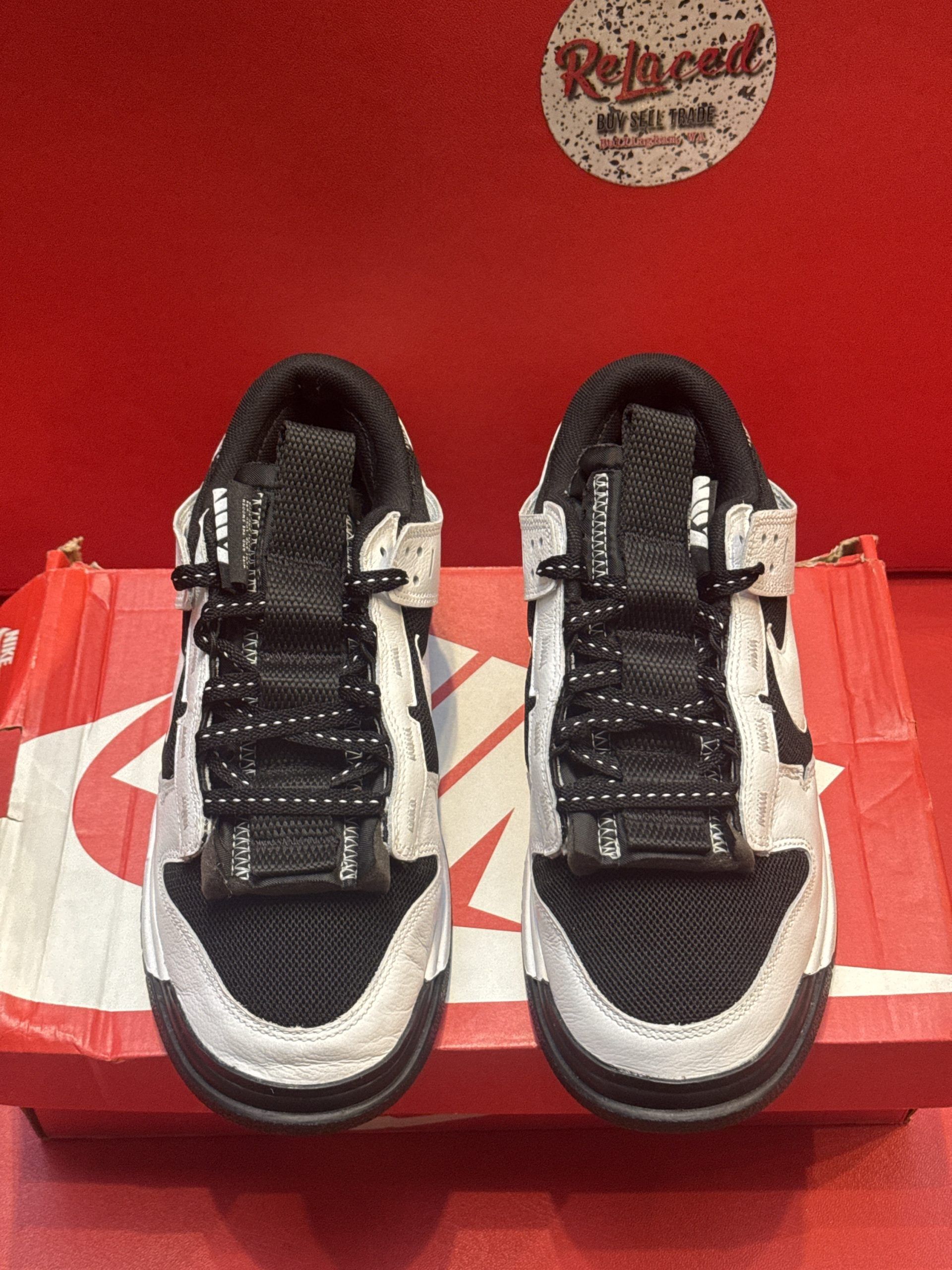 Nike Dunk Low sneakers, black and white, on top of a red shoe box.