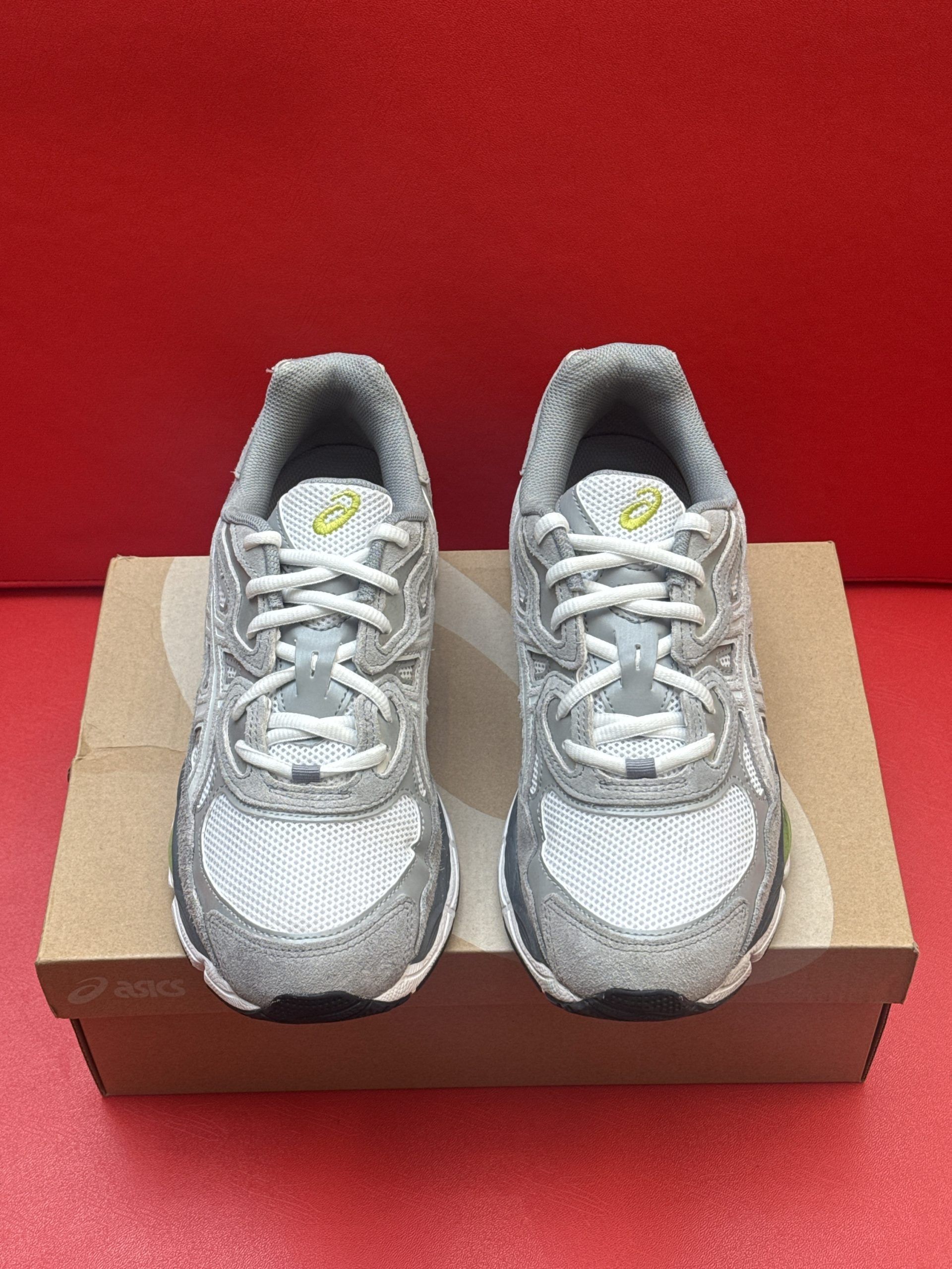 Silver and gray Asics running shoe on a box, sole of second shoe visible.