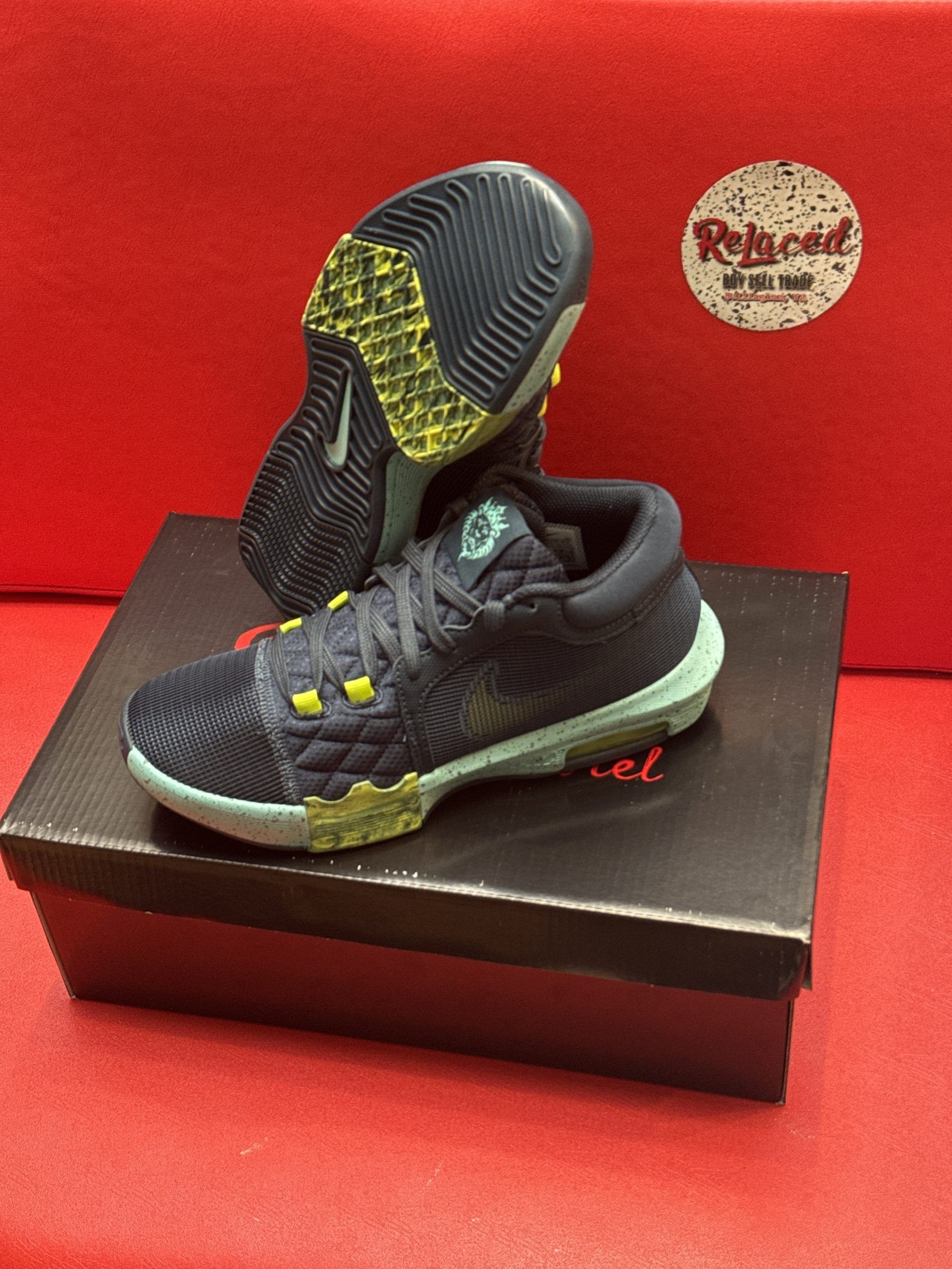 A pair of blue and green Nike basketball shoes on top of a black shoebox, against a red background.