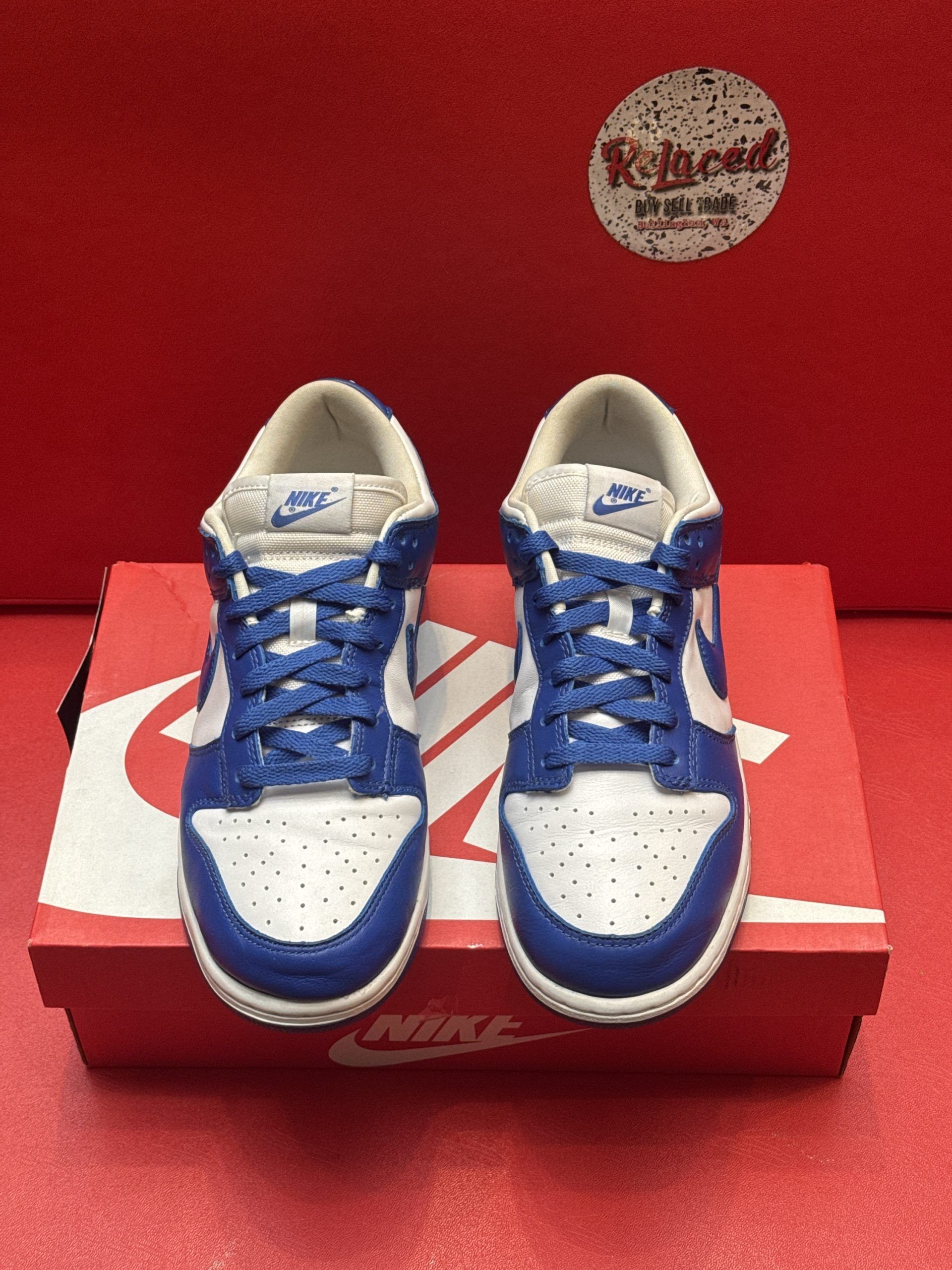 Blue and white Nike Dunk Low shoes on a red Nike box, with a blue sole visible.