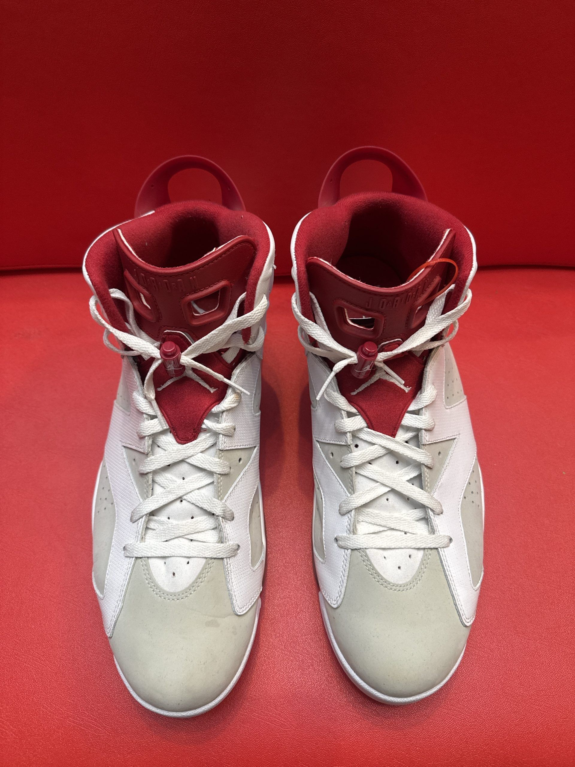 White and red Air Jordan 6 sneakers on a red surface; sole visible.